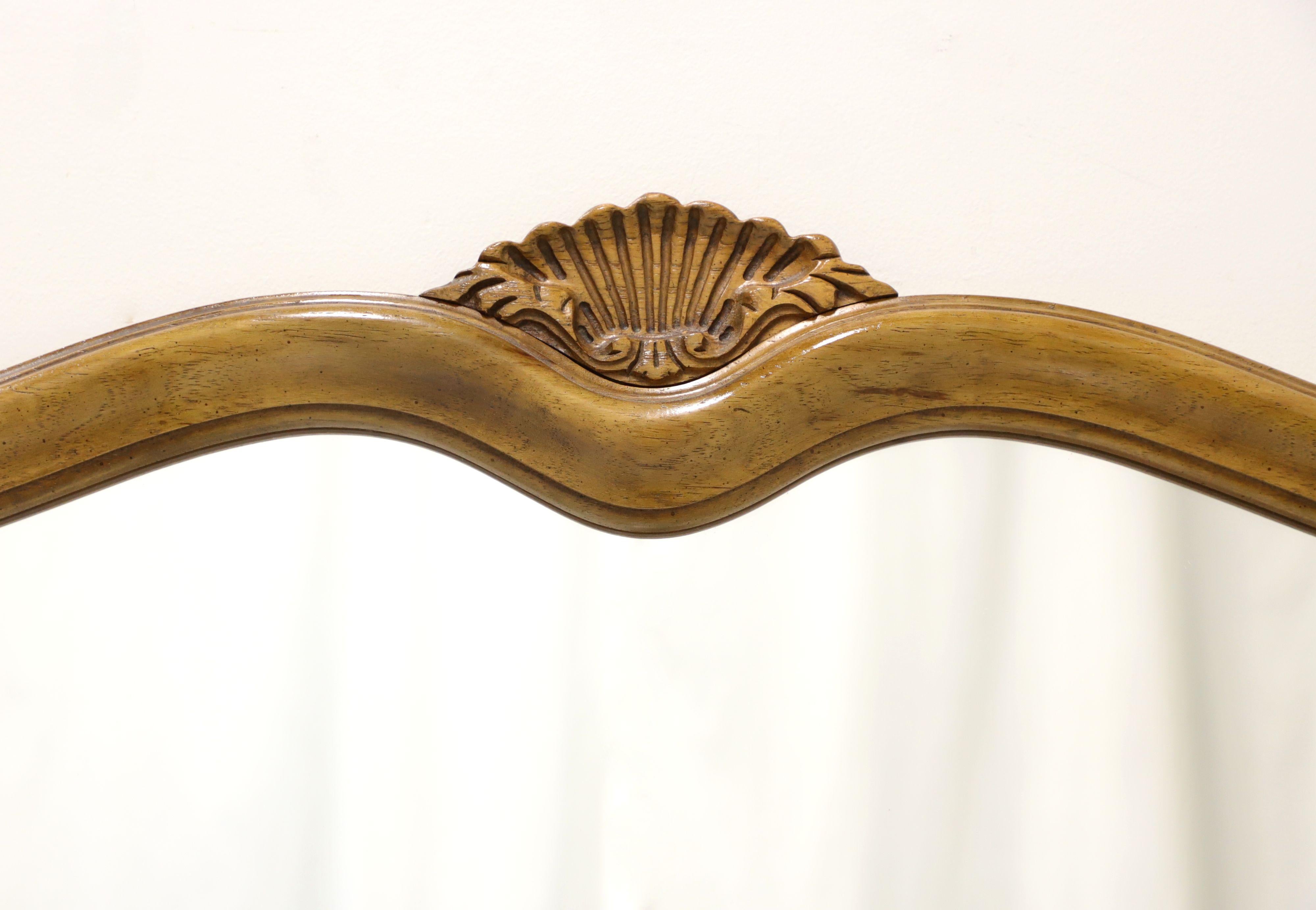 An over dresser or wall mirror in the French Country Louis VX style, unbranded, similar quality to Thomasville. Mirror glass in a serpentine shaped solid hardwood frame with decorative shell carving to top center. Made in the USA, in the mid 20th