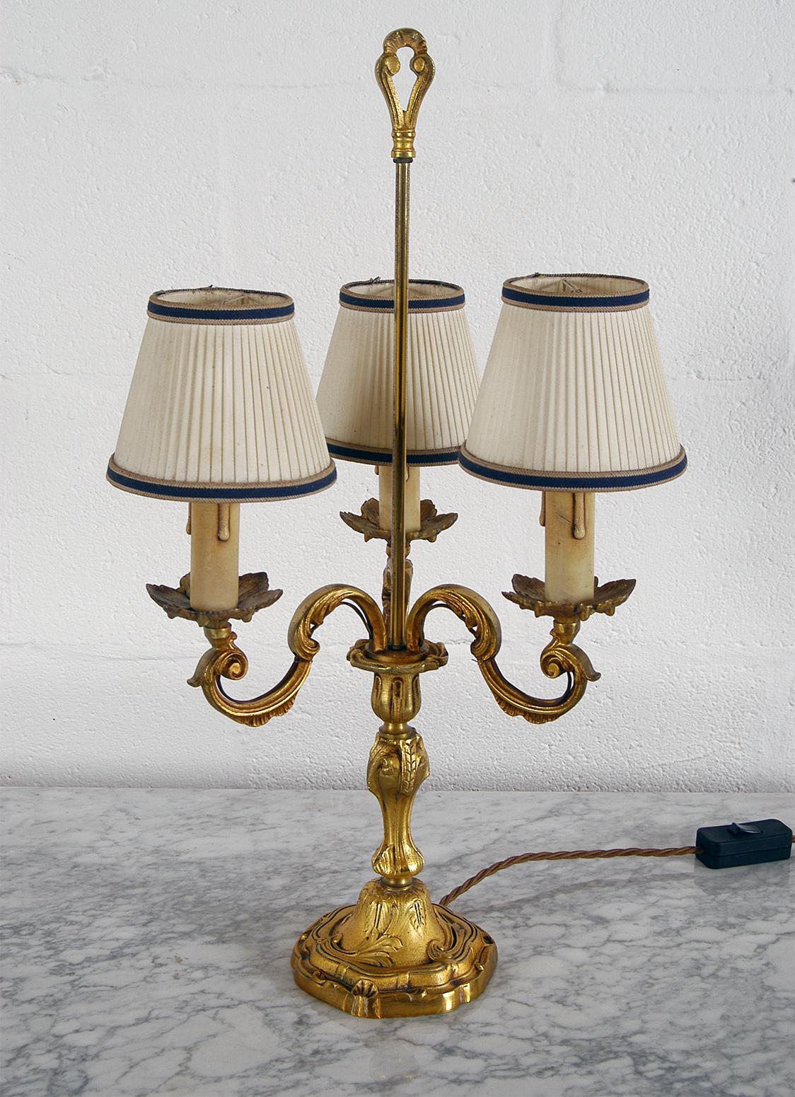 A mid-20th century French gilt brass three-arm table lamp, retains its original pressed card faux candles and is fitted with three individual chandelier shades.
The heavy brass base has a mark on the underside (L333 / 335) and has been gently