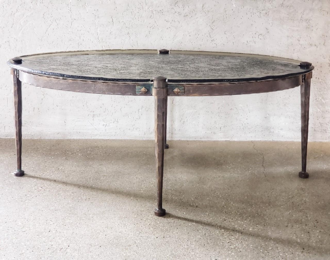 Mid-20th century French hand forged iron and custom water glass coffee table.
This hand forged iron table is quite elegant with its lovely slim legs and simple feet. 
It touts a textural finish that of which, appears to be hand chiseled.  Finished