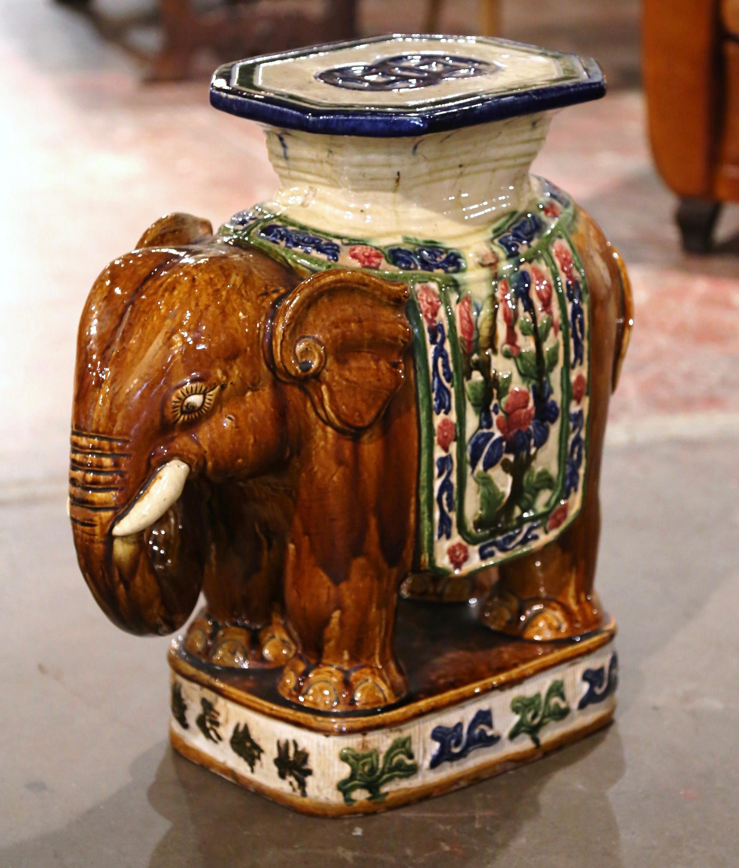 This colorful vintage porcelain garden seat was found in France. Crafted circa 1960, the large ceramic seating shaped as an elephant with his trunk lowered is heavily decorated in oriental finery; the colorful mammal has a rectangular seat at the