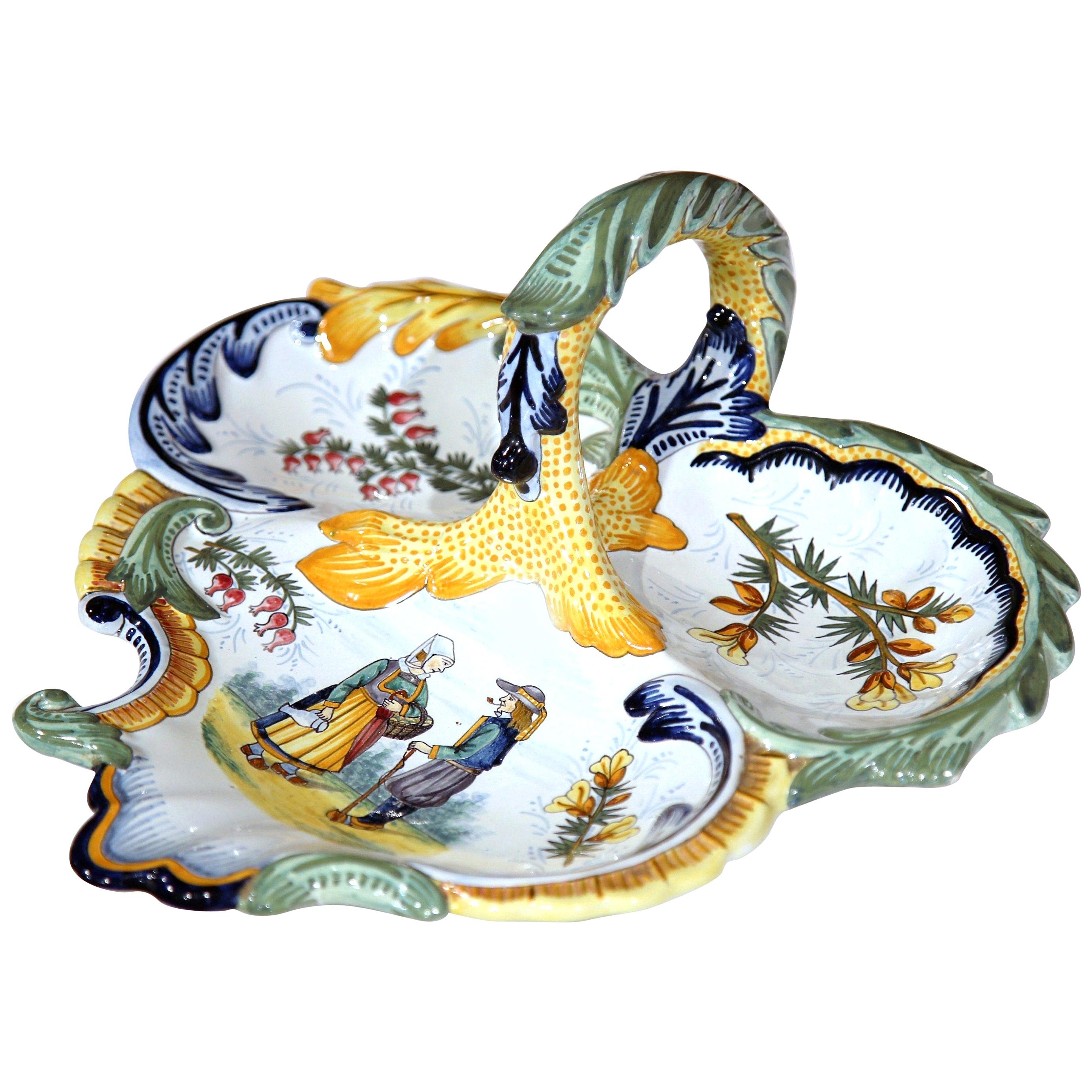 This colorful, antique Quimper dish with central handle was sculpted in Brittany, France, circa 1950. Shaped as a heart, the porcelain tray features three unique food compartments decorated with hand painted flowers and a Briton couple dressed in