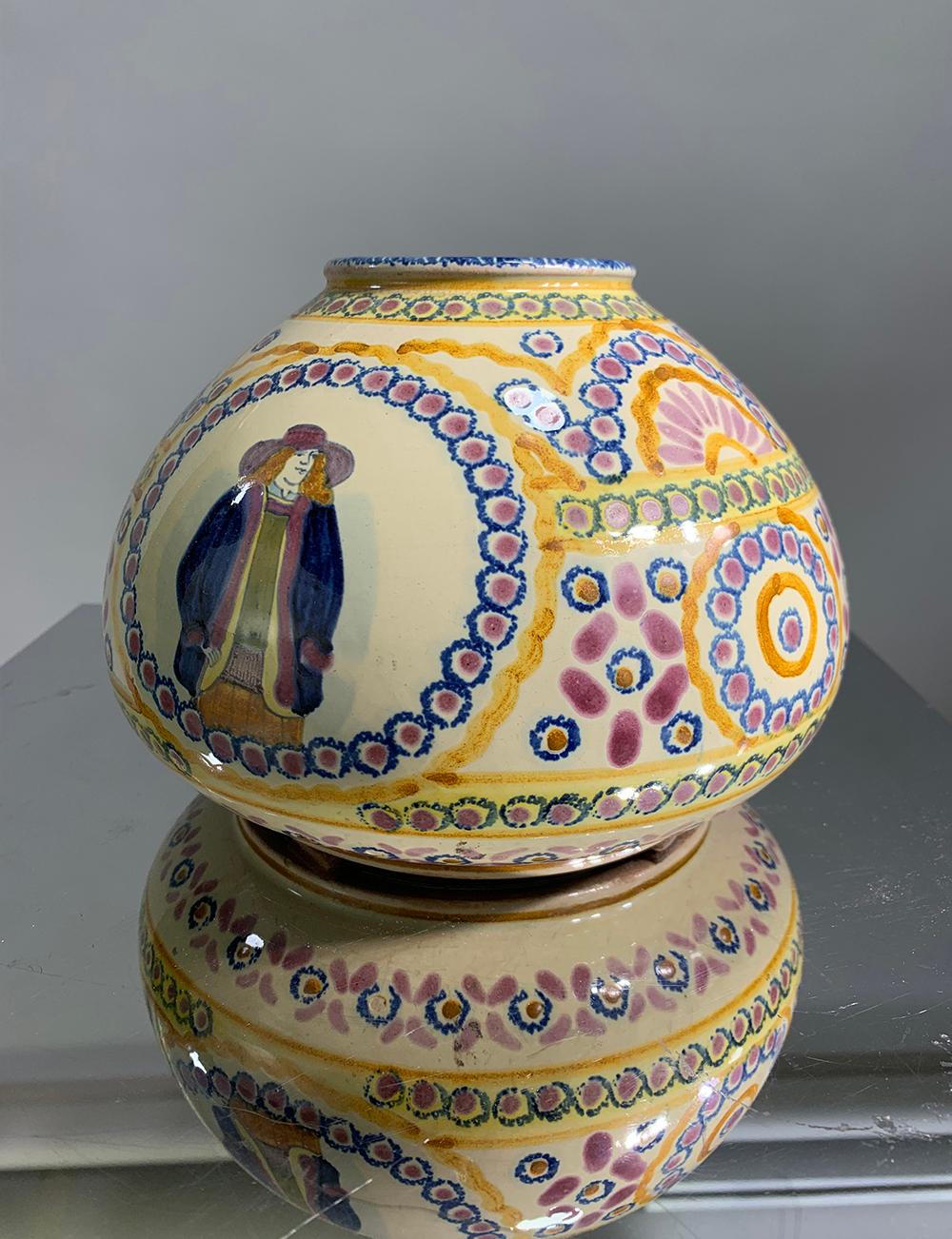 This beautiful faience piece features colorful hand painted decor. The painted elements include a framer dressed in traditional, historically accurate clothing with floral decor .
The vase is in excellent condition and is signed and numbered on the