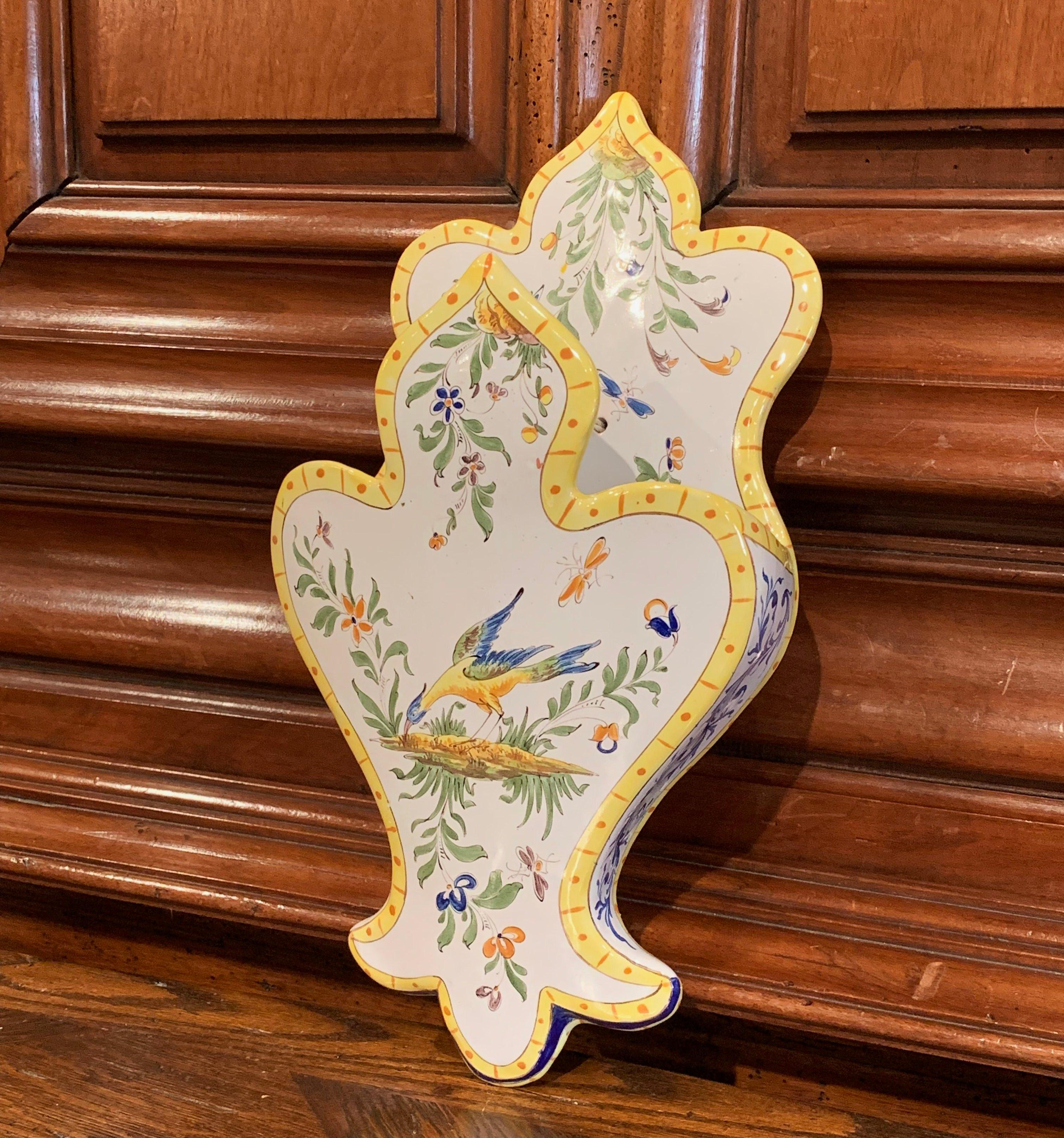 Decorate a wall or a shelf with this elegant antique ceramic letter holder from Normandy, France; crafted circa 1950, the colorful wall piece with scroll shapes features hand painted decorations including bird, flowers and foliage. The faience piece