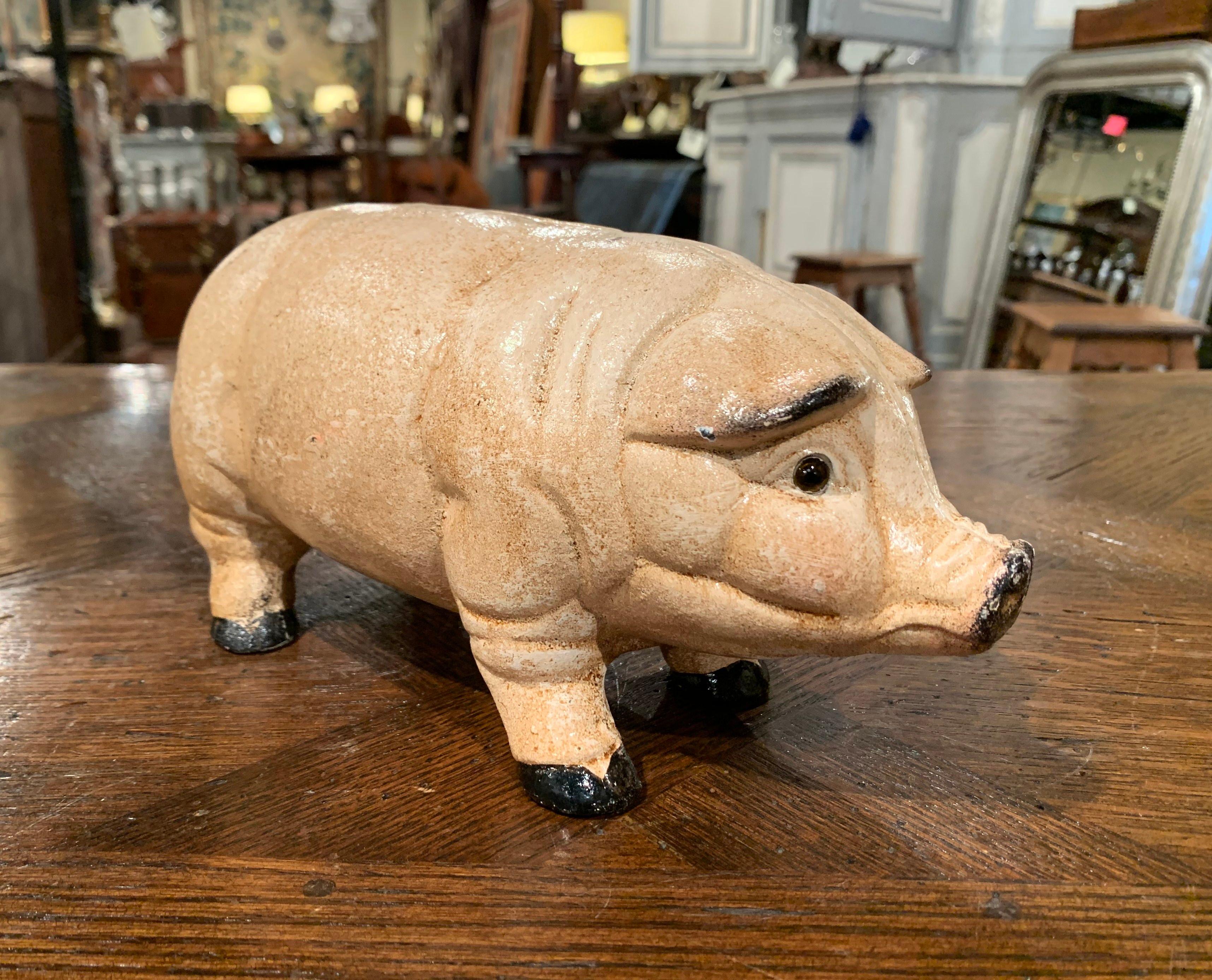 Crafted in France, circa 1960, the hand painted iron pig sculpture equipped with a slot for coins at the top, has a beautiful beige patinated finish, and very realistic shape and details. The piggy bank figure is in excellent condition overall, and