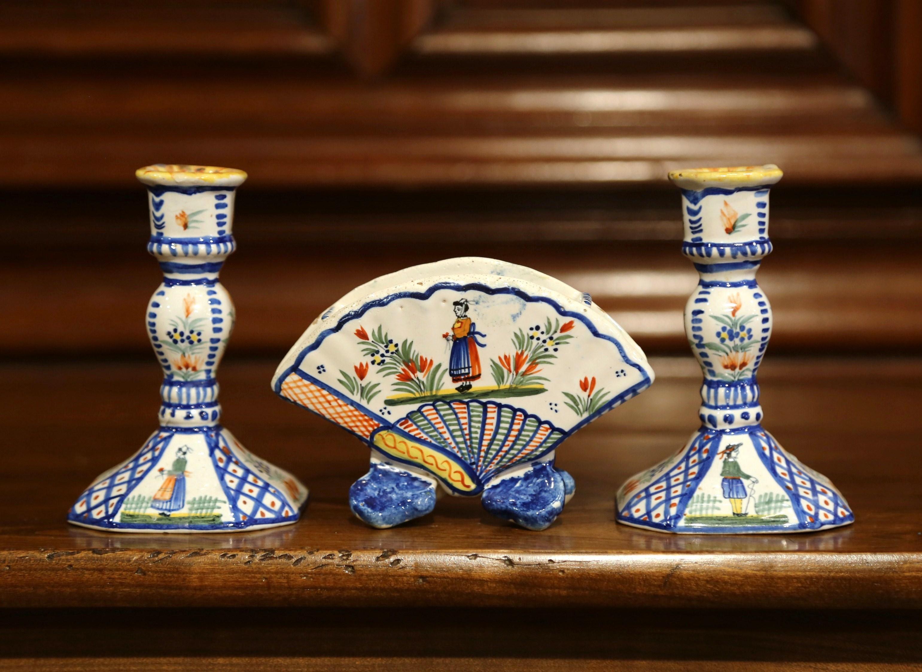 Decorate a shelf with these three faience pieces from Quimper, crafted by Henriot in Brittany, circa 1950, the colorful set includes two candlesticks with hand painted Breton figures and floral decor, and a matching flower vase with Breton woman.