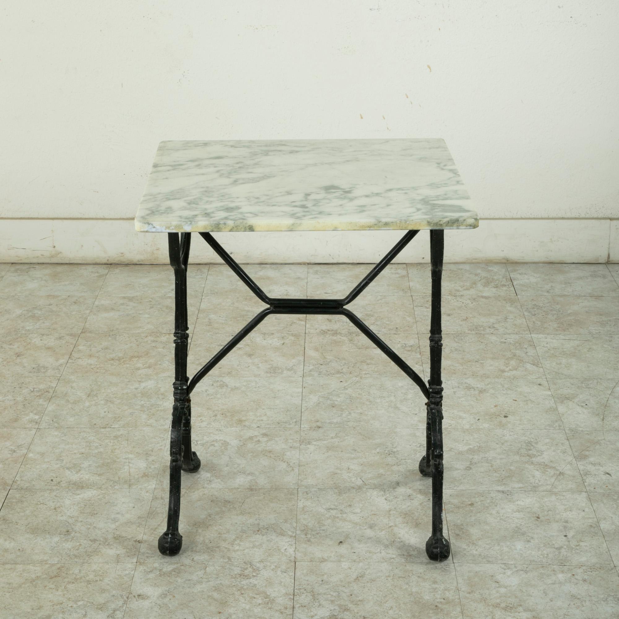 Originally used in a French brasserie during the mid-twentieth century, this cast iron bistro table or cafe table features a solid 23.75 inch square white marble top with grey veining. Scrolled iron legs support the top and are joined by an