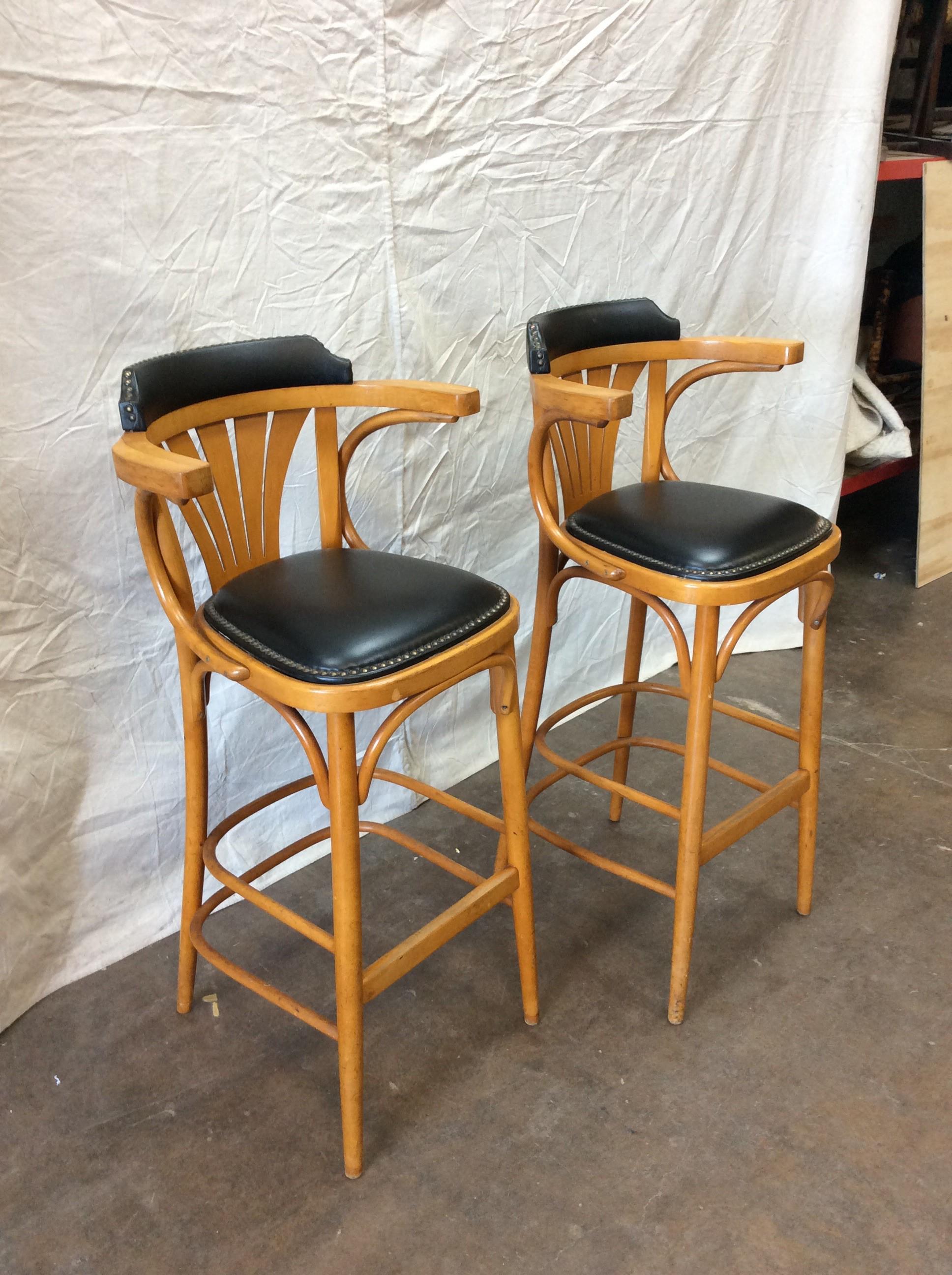 Found in the South of France, these Mid-20th century French Leather Counter or Barstools feature a beautiful wooden construction with upholstered black leather seats and backrest. The back of these stools are constructed with a unique slatted back