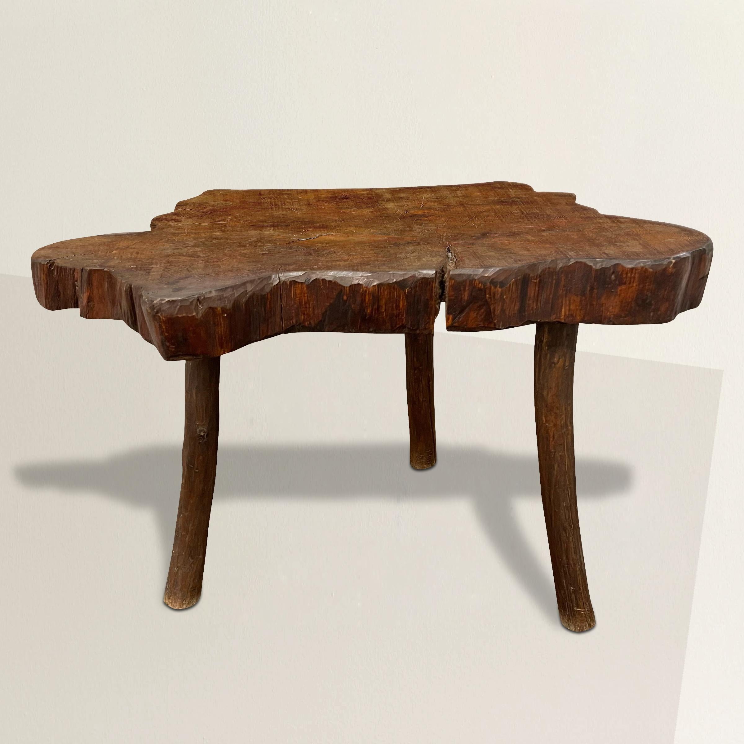 A beautiful mid-20th century French modern live-edge center table with a top made from one cross-section slab of a tree supported by three legs. The perfect table next to the sofa at your lake-side cottage, a console table in your chic city