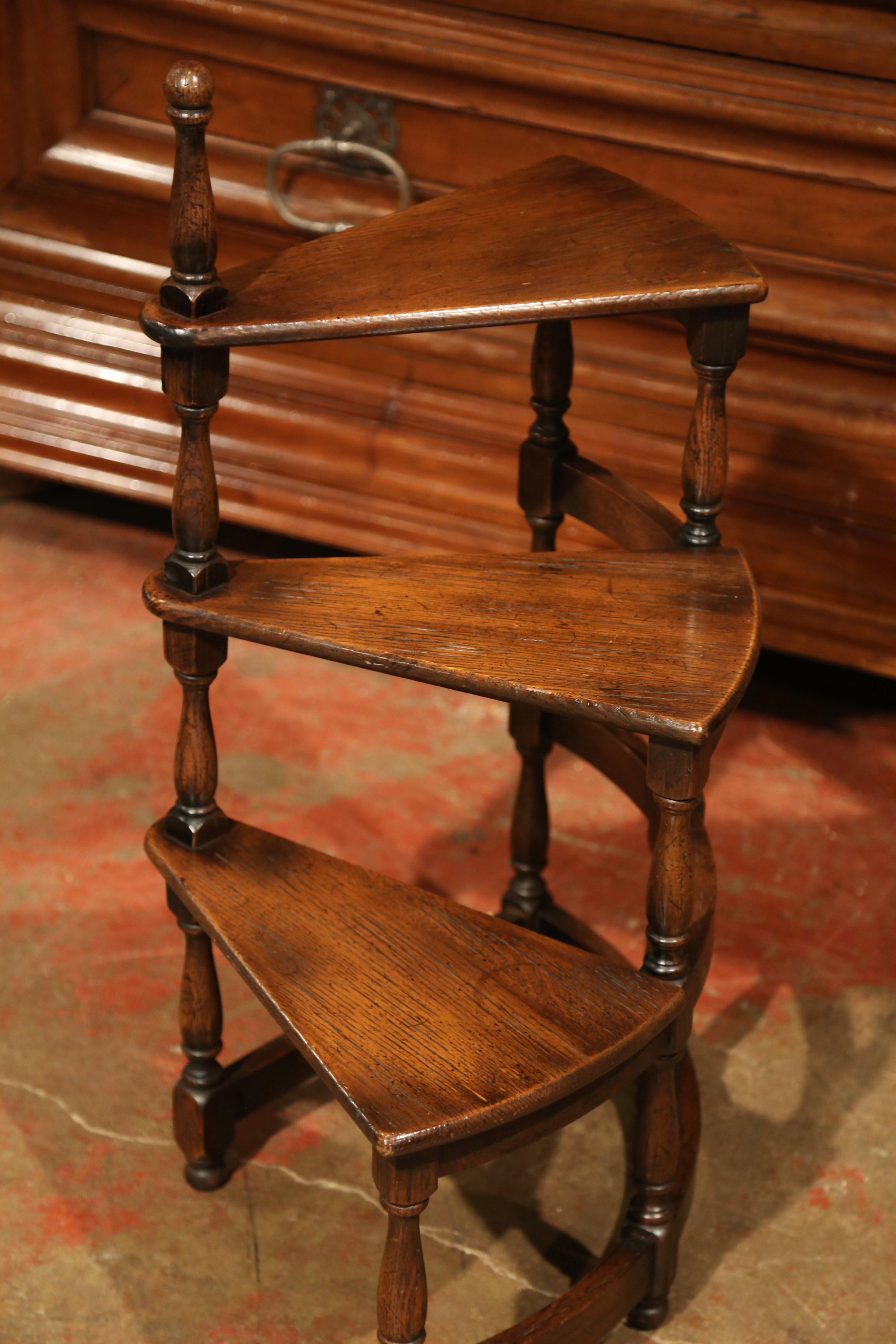 Use this vintage oak staircase element to organize books in your office or library. Created in France circa 1950, the small circular step ladder sits on four small feet and each of the three stairs roll around a turned, central post. The elegant