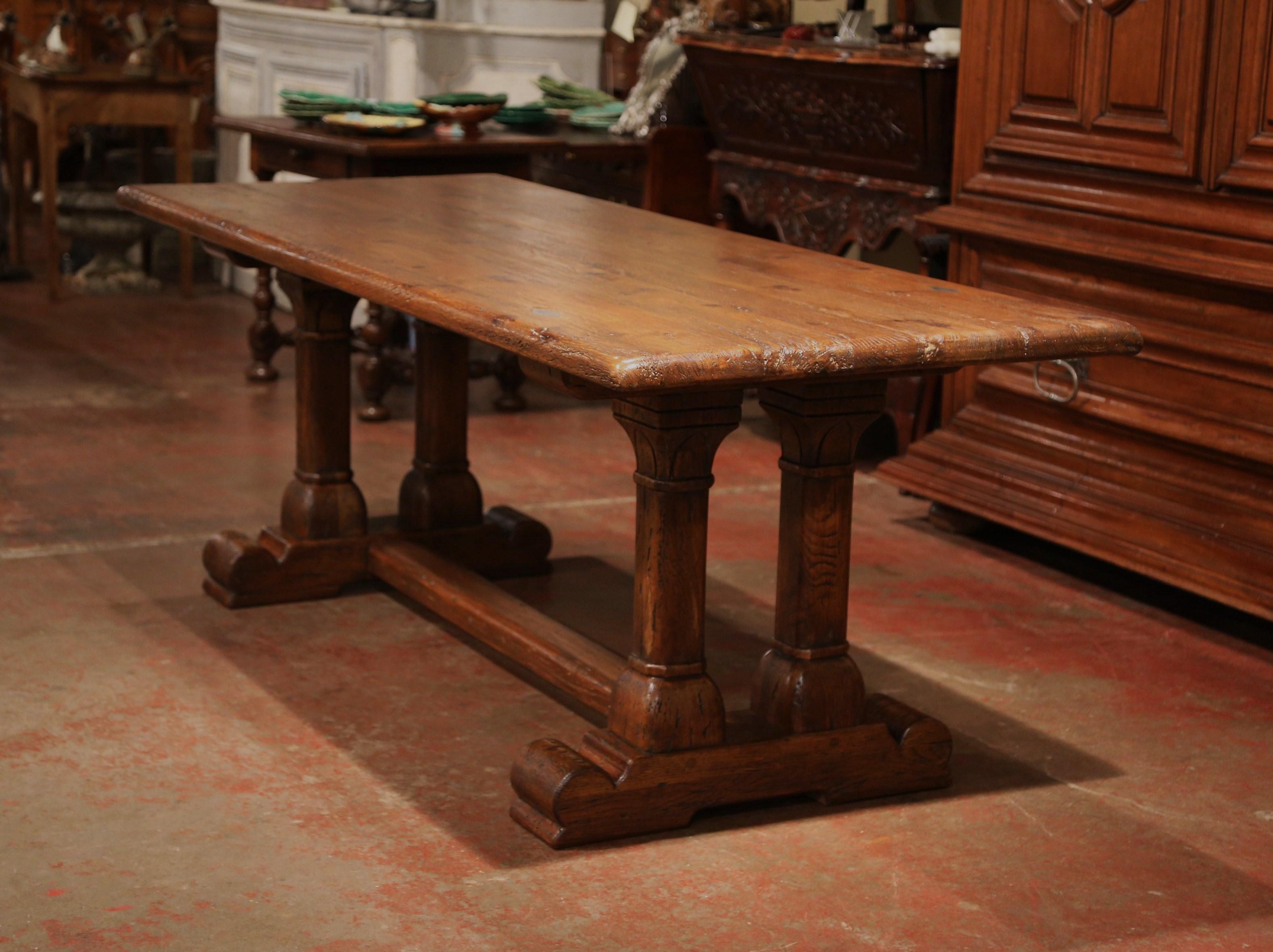 Crafted in Normandy, France circa 1960, this sturdy, rectangular trestle table would make a useful, traditional addition to any breakfast room. The carved oak dining room table sits on a trestle base with two carved, double pedestal legs embellished