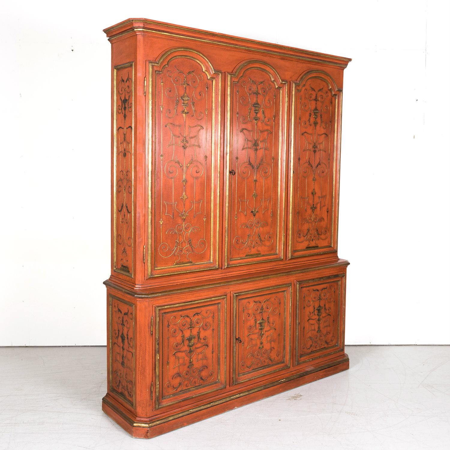 A vintage mid-20th century red lacquered French Louis XIV style buffet deux corps having chinoiserie motifs hand painted in a raised pigment style in parcel gilt, circa 1940s. The upper cabinet features three carved raised panel arched doors that