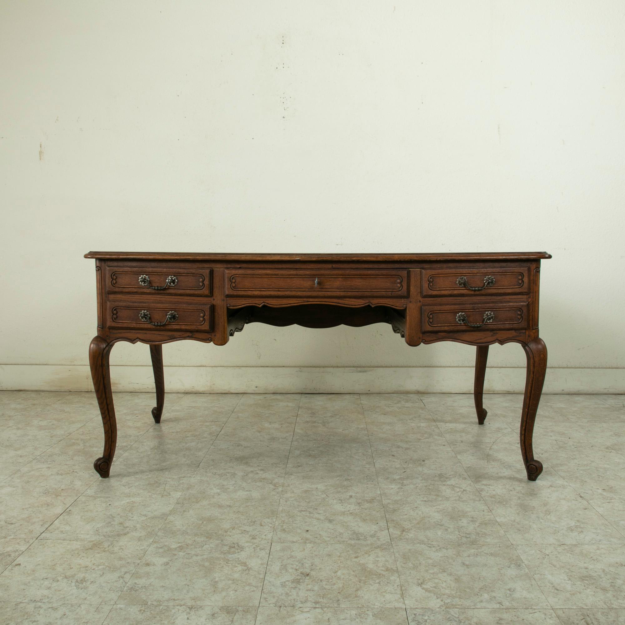This mid-twentieth century French Louis XV style oak desk features a parquet top and hand pegged paneled sides. The desk is fitted with five drawers of dovetail construction each appointed with an iron drawer pull. The central drawer may be locked
