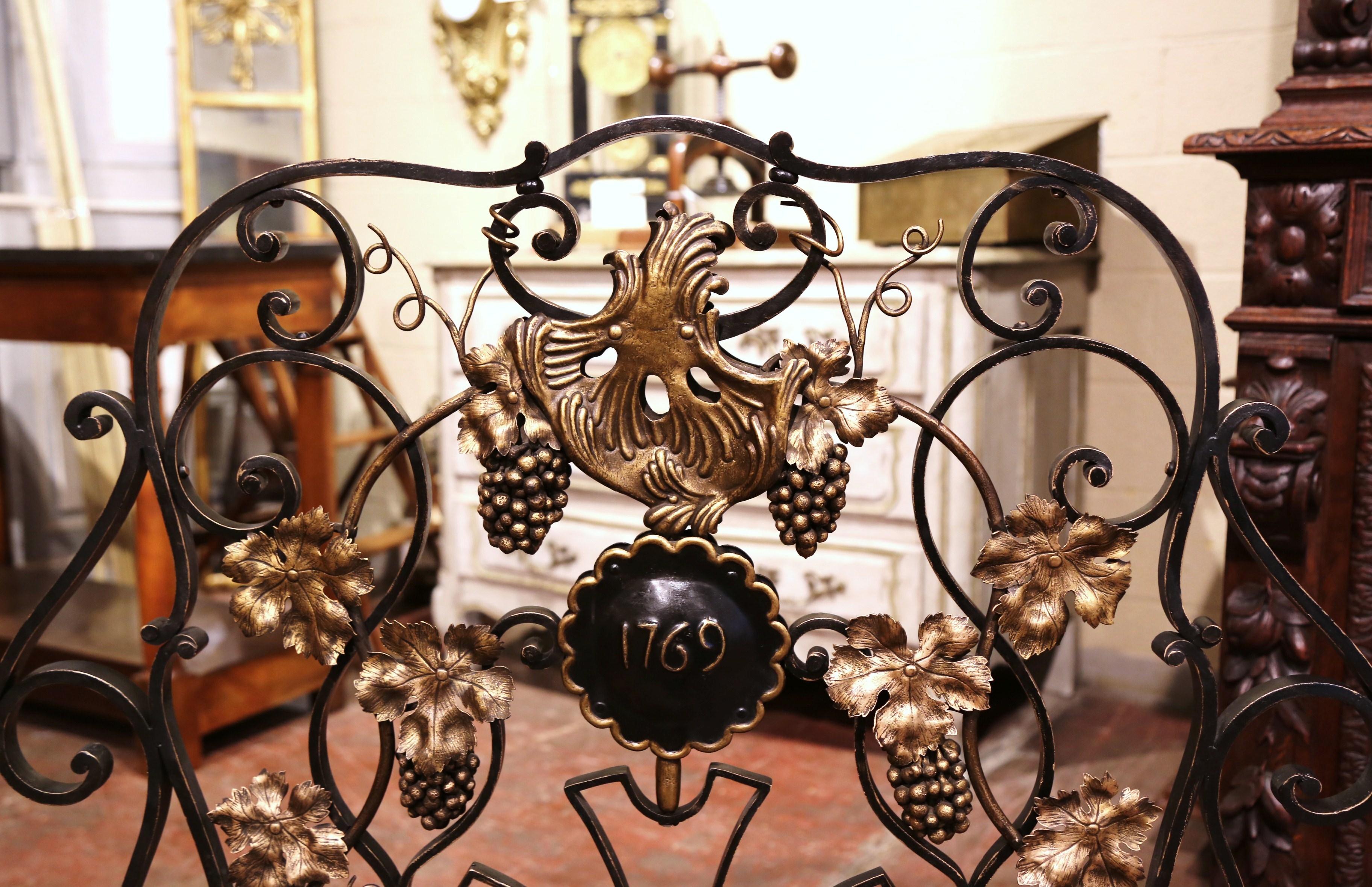 Decorate a fireplace hearth with this elegant freestanding antique iron screen. Forged in France circa 1950, the decorative screen with serpentine top stands on scrolled feet and is heavily decorated with grape and leaf motifs in high relief; it is