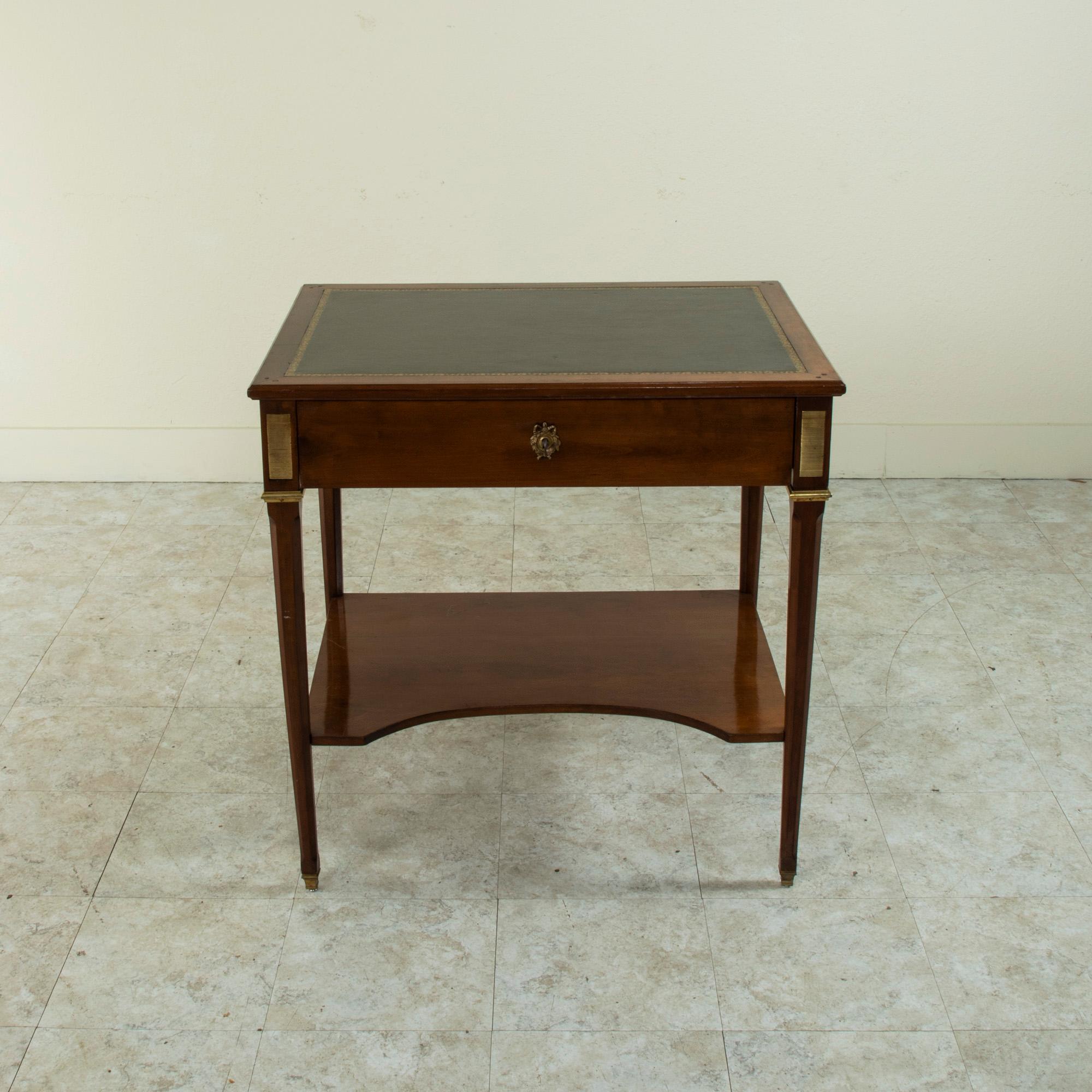 This mid-20th century Louis XVI style fruitwood side table or end table features a gold tooled green leather top and a drawer with a drop down pullout writing desk. Its drop down surface locks using its own key. Striated bronze plaques adorn the
