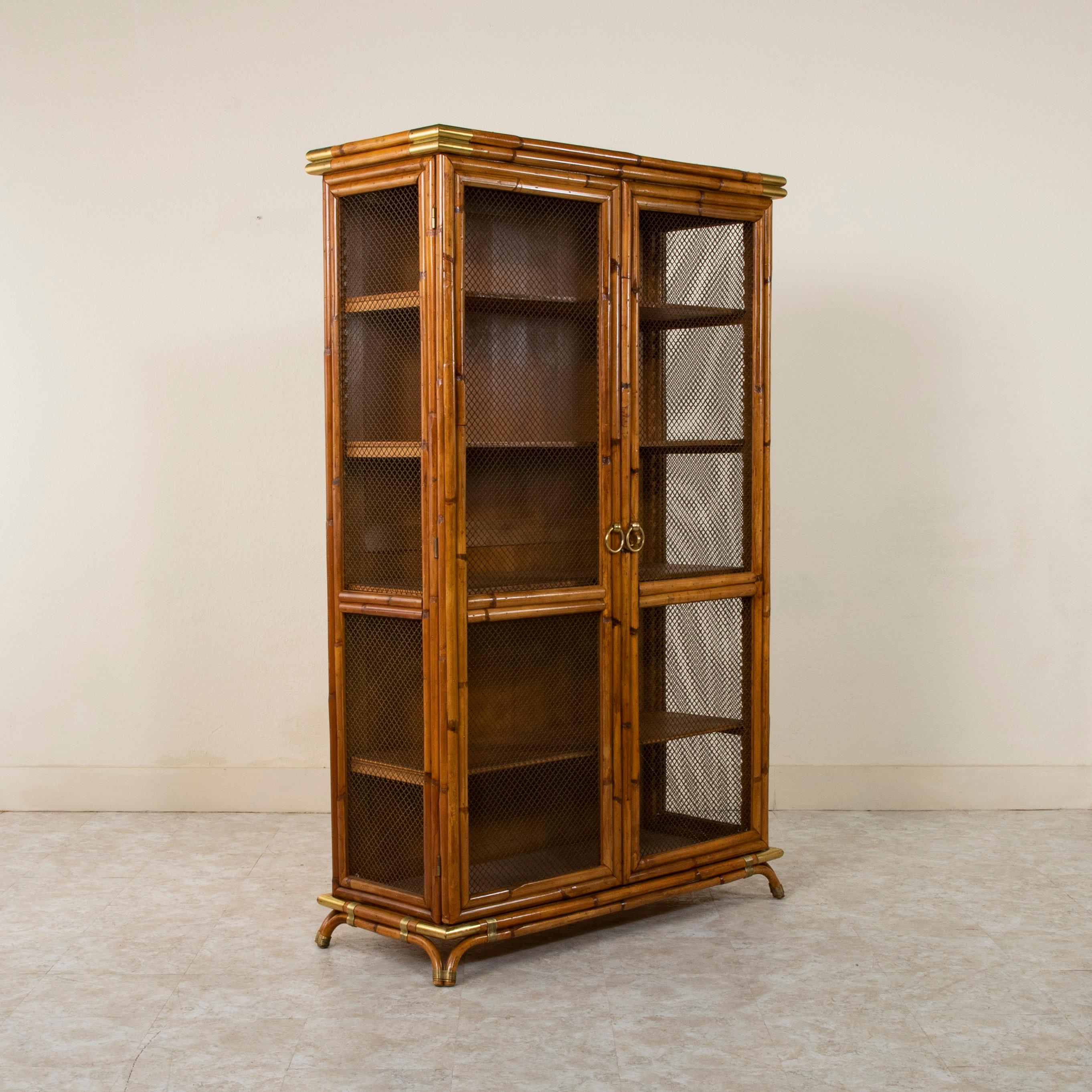 Attributed to Louis Sognot (1892-1970), designer for Maison Jansen, this mid twentieth century bookcase or vitrine is constructed of bamboo and features bronze wire on the front and sides. The corners of the piece and curved feet are all capped in