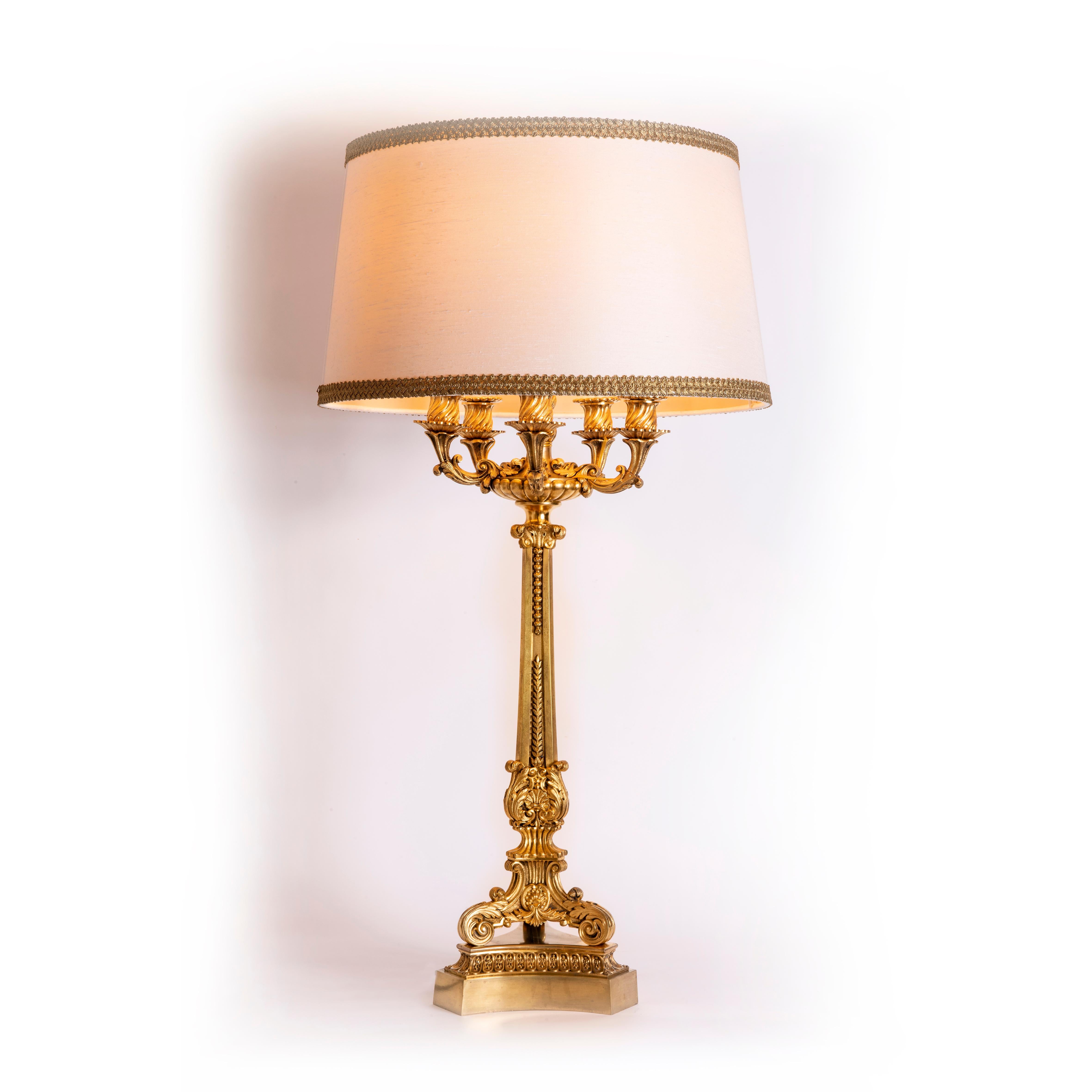 A great quality mid 20th century cast gilt bronze table lamp with finely chased Neoclassical detailing. Tripod base supports a tapered shaft with decorative mounts, surmounted by a five armed candelabra top.
Of French origin, the provenance of this