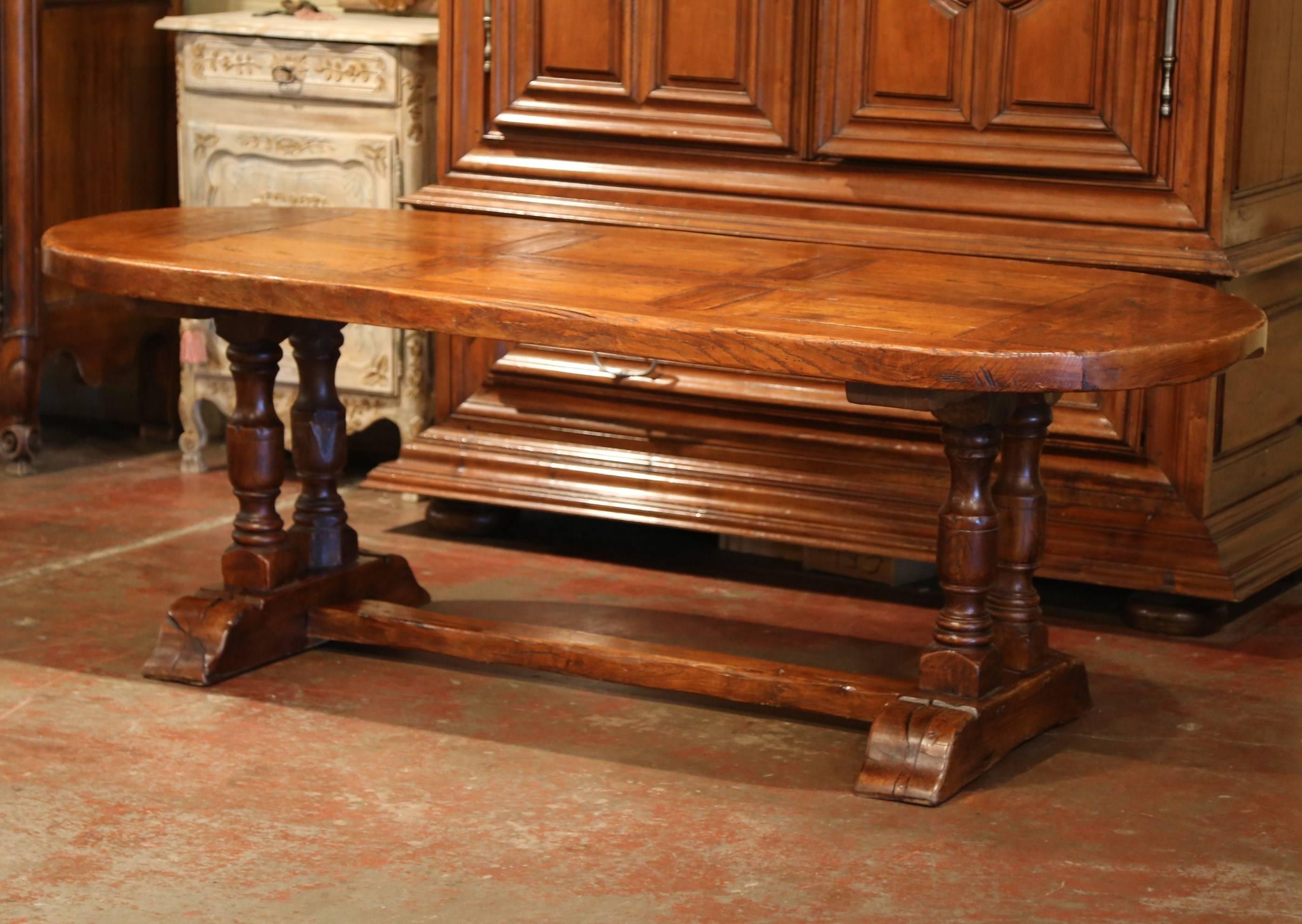 Crafted in Normandy, France circa 1950, this oval breakfast room table features a double-pedestal base with four turned legs. The rustic thick top has a geometric parquetry design with six rectangular panels in the center and demilune panel at each