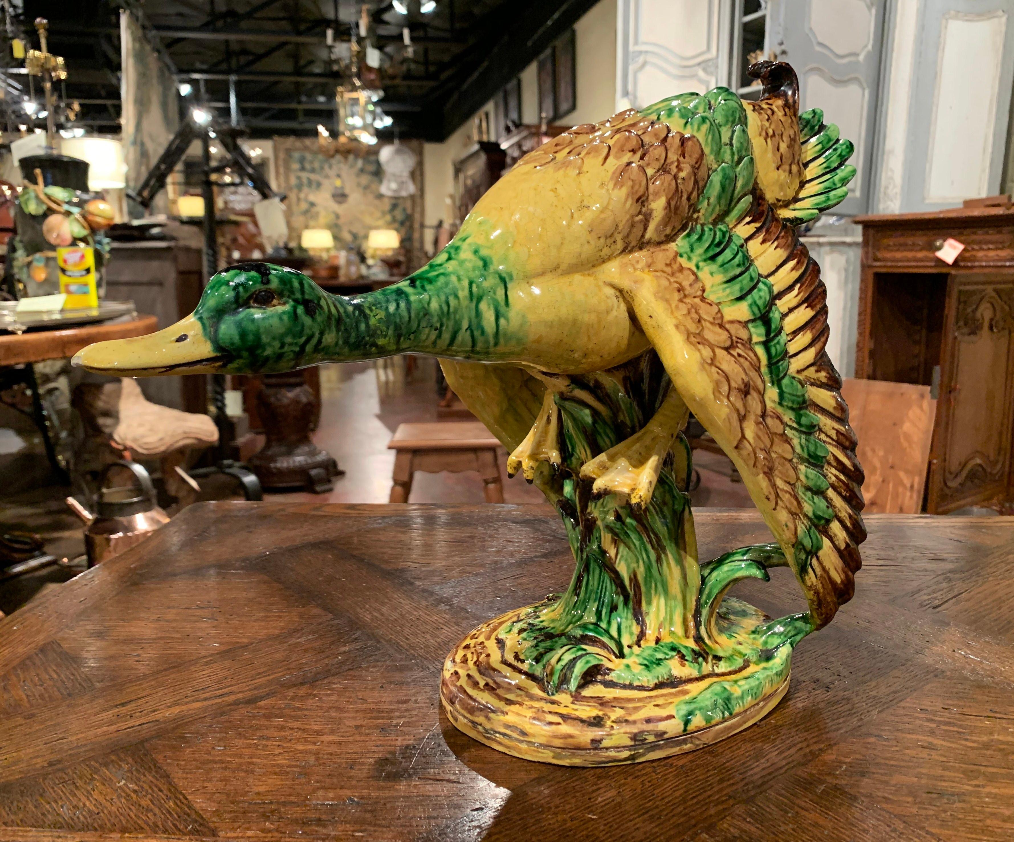 Decorate a man's office or a game room with this elegant antique Majolica duck sculpture; crafted in France circa 1960, the piece features a duck standing on a tree shape base and getting ready to take off. The large sculpture is in excellent