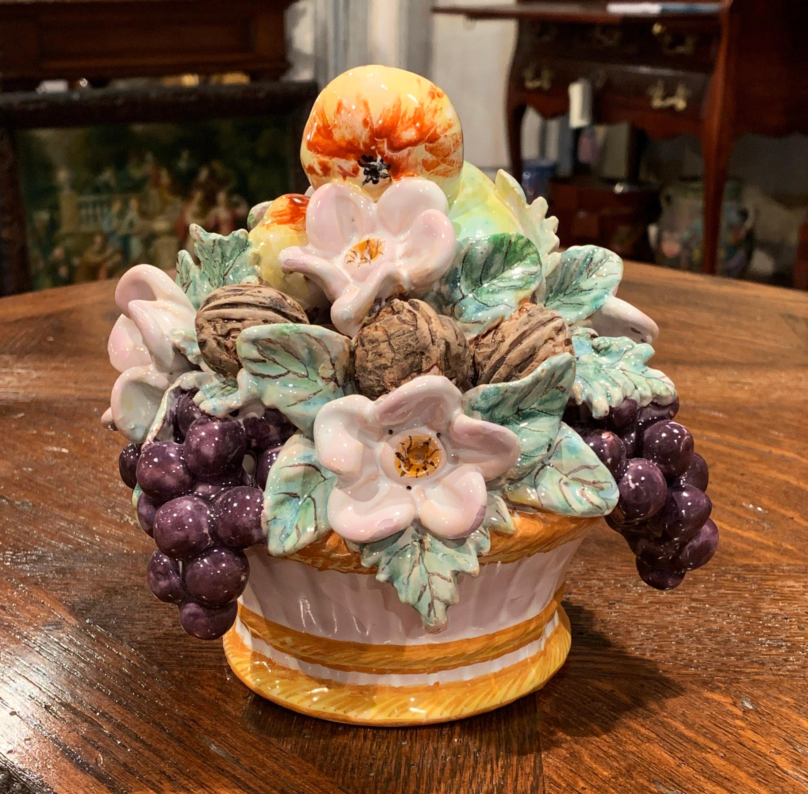 Decorate a tabletop or a chest with this colorful, Majolica basket composition. Crafted in France, circa 1960, the ceramic centerpiece features a realistic assortment of fruits and flowers in high relief set inside a white basket decorated with