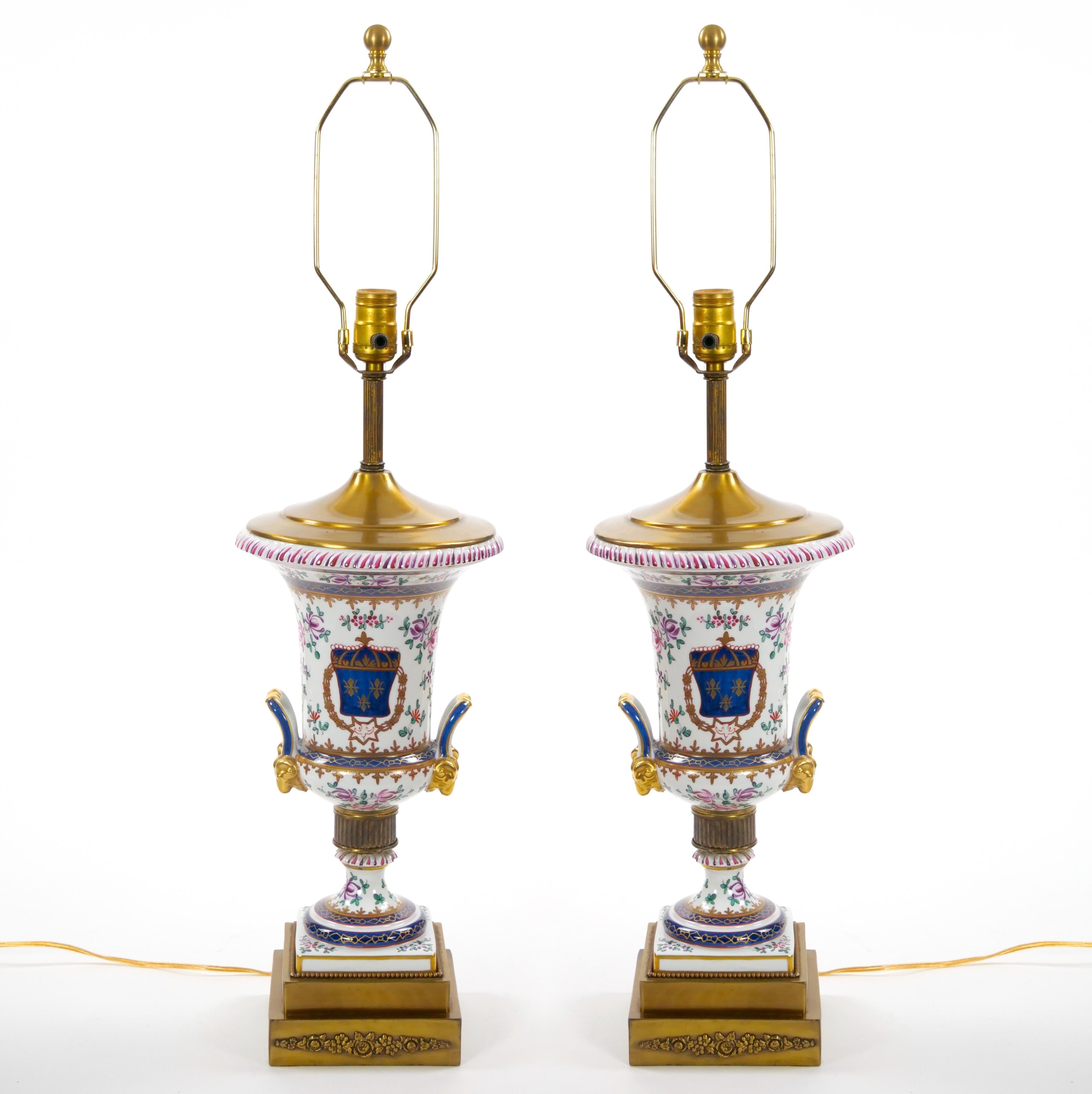 These exquisite mid-20th century French porcelain table lamps feature stunning hand-painted floral and foliate designs, beautifully accented with gilt gold details. Each lamp showcases a soft palette of pinks, purples, greens, and blues, set against