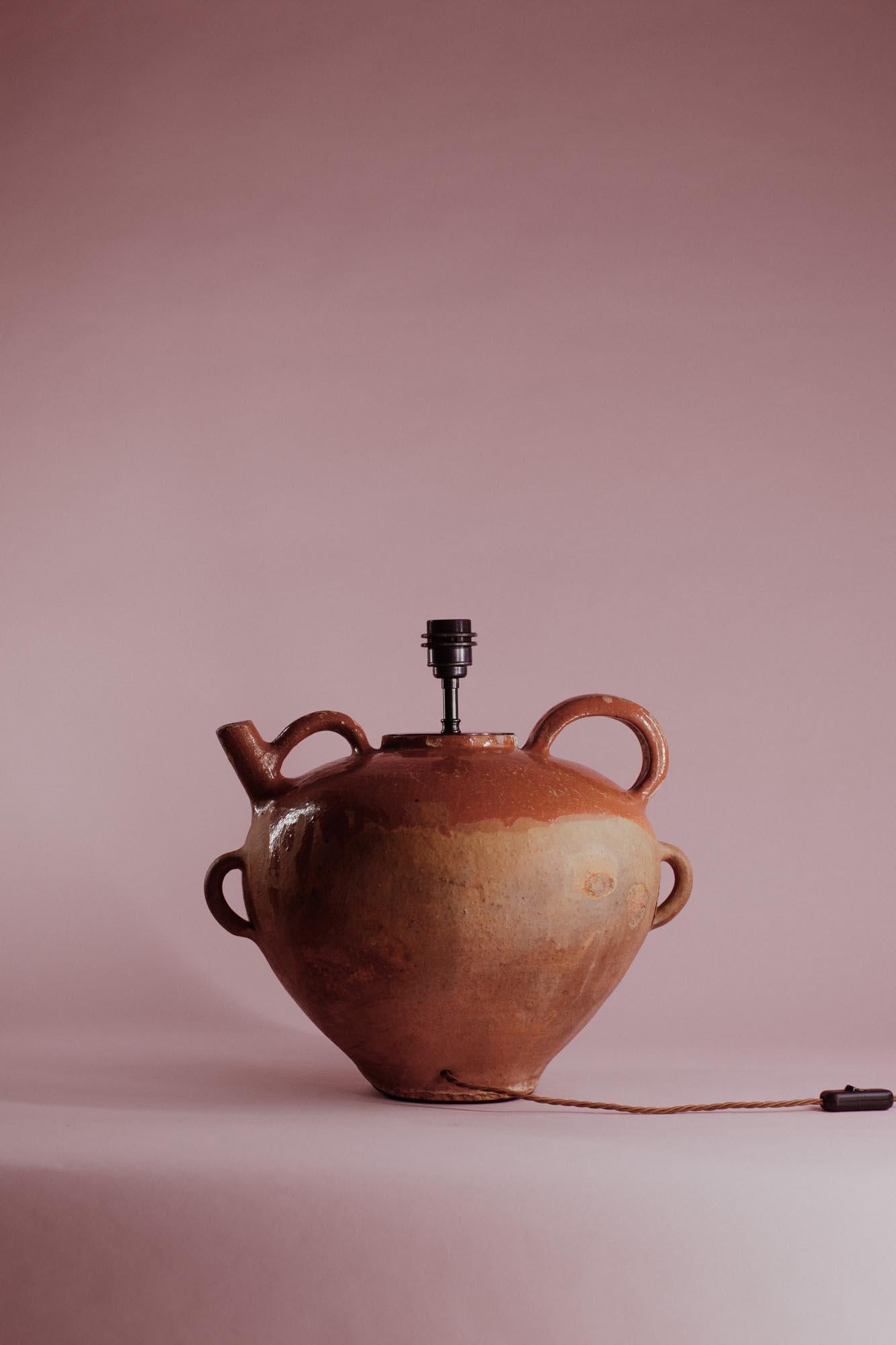 Ce pot vintage en terre cuite de Provence, France, capture la beauté chaude et tactile de la poterie méditerranéenne traditionnelle. Autrefois utilisé pour stocker l'huile d'olive ou le vin, sa forme épaisse et arrondie et son bec verseur