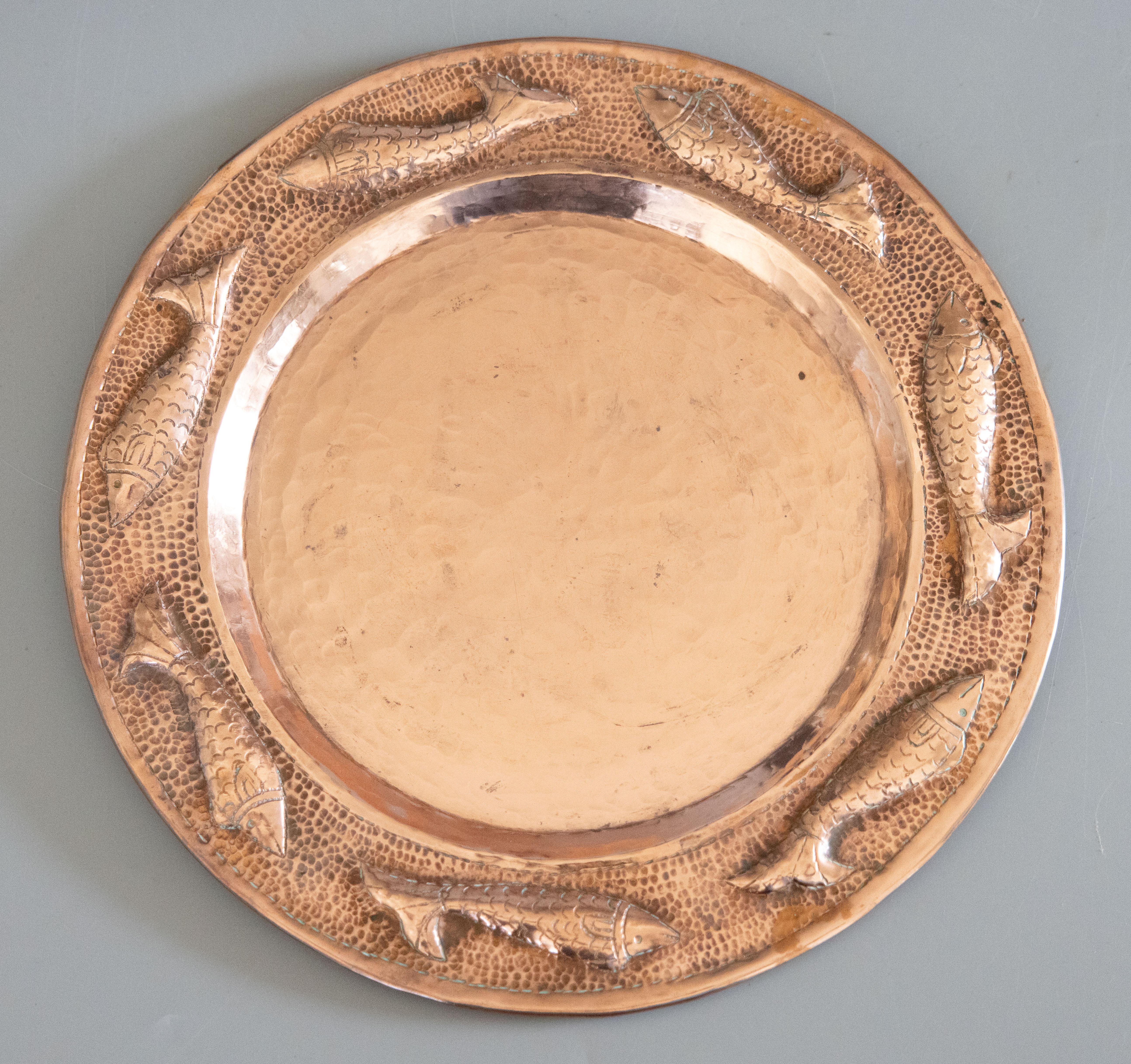 Un delizioso caricatore / piatto / placca / appendiabiti da parete in rame martellato repoussé francese di metà secolo, proveniente da Parigi, Francia, circa 1950. Ha un incantevole bordo a forma di pesce, un design martellato a mano in una patina