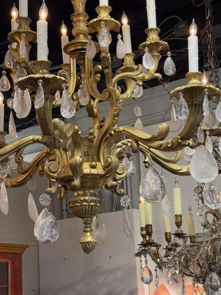 Eleva l'atmosfera di qualsiasi spazio con questo lampadario in bronzo rococò francese della metà del XX secolo e cristallo di rocca. La squisita lavorazione riflette un'eleganza senza tempo, con la calda luce del bronzo che completa il design