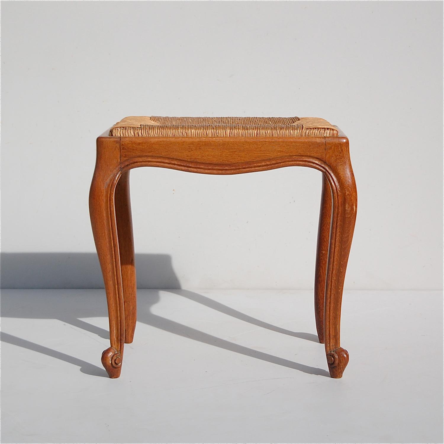 This French, vintage, rectangular stool, piano stool or seat with rush seat has been carved from solid oak and is a 1950s interpretation of the Louis XV design style. It has cabriole legs ending in scroll feet.