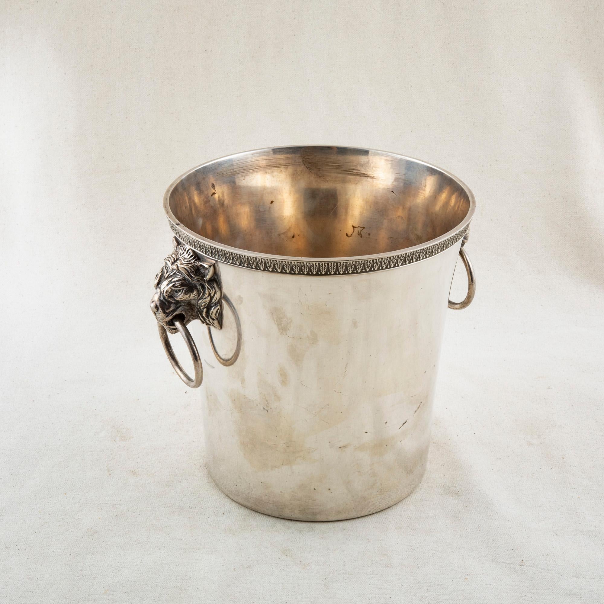 This mid-twentieth century French silver plate over bronze champagne bucket features a lion's head on each side with a drop ring handle. The bucket is stamped with a star hallmark on the bottom and the number 24. A beautiful addition to any bar,