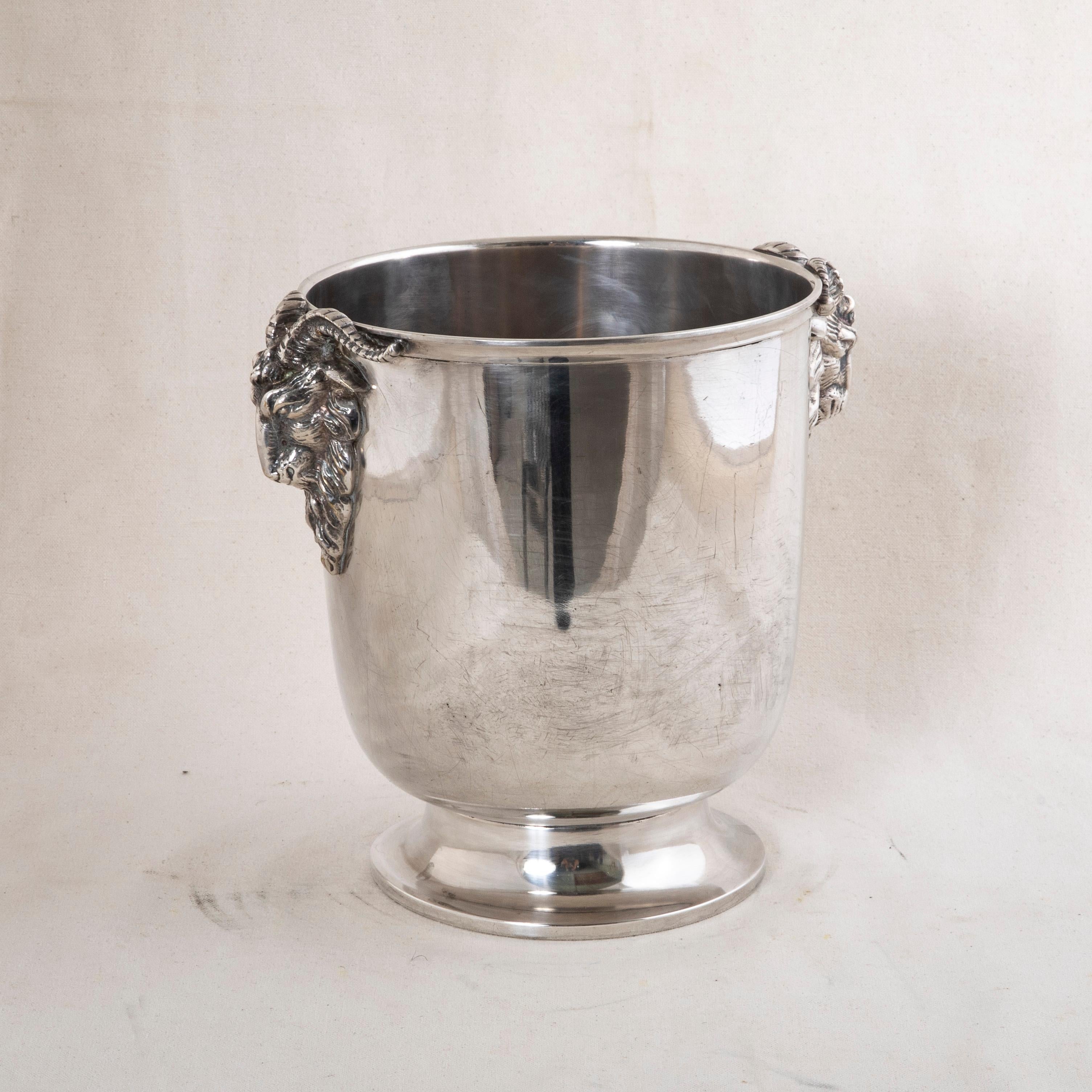 Esta champanera francesa plateada de mediados del siglo XX tiene un asa en forma de cabeza de carnero a cada lado y una base con pie. El cubo tiene un sello de calidad en la parte inferior. Un bello complemento para cualquier bar, hacia 1960.