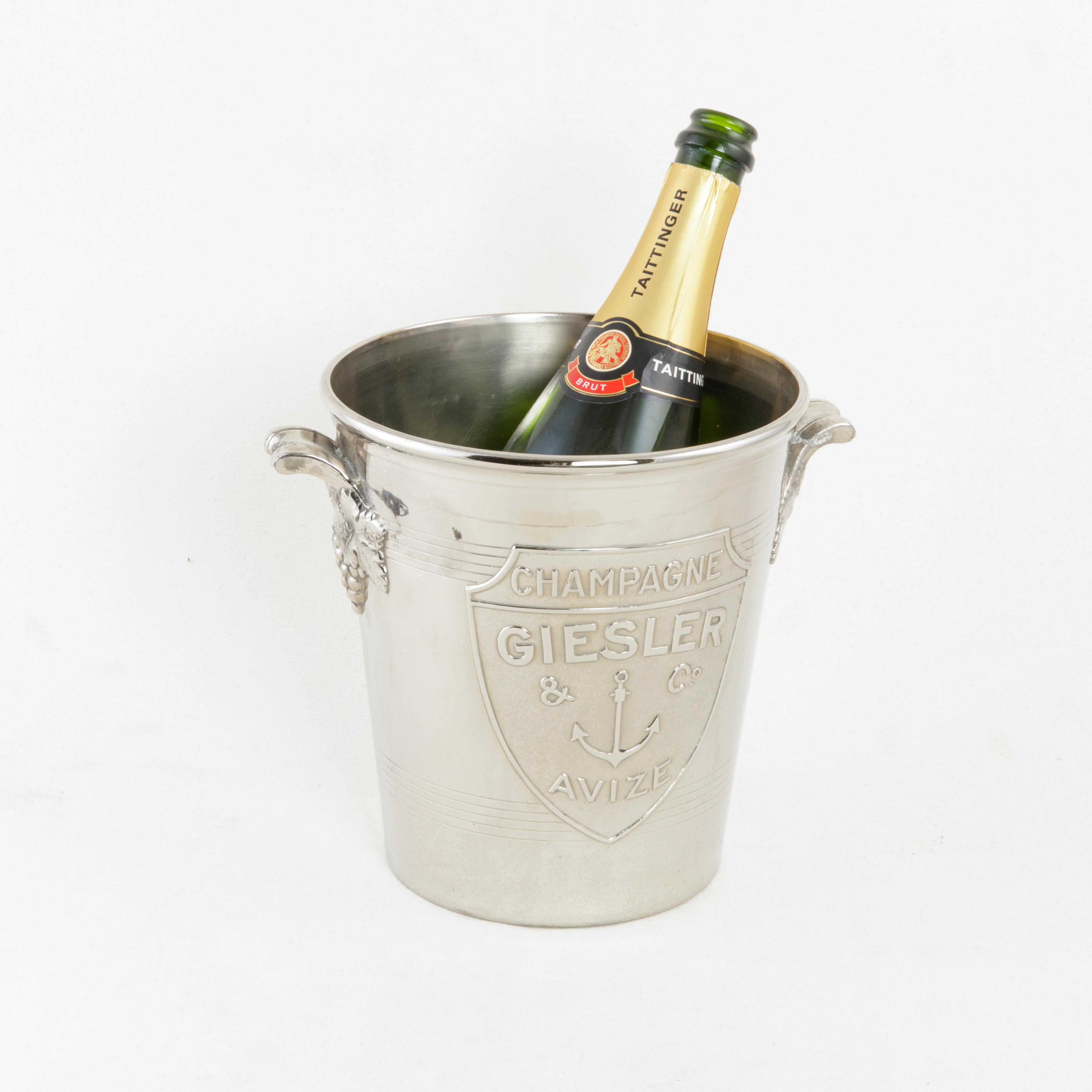 This mid-20th century French silver plate champagne bucket features a shield on one side with the name of the champagne producer, Giesler & Co and the name of its town of origin Avize below. At the center of the shield is an anchor. The Giesler