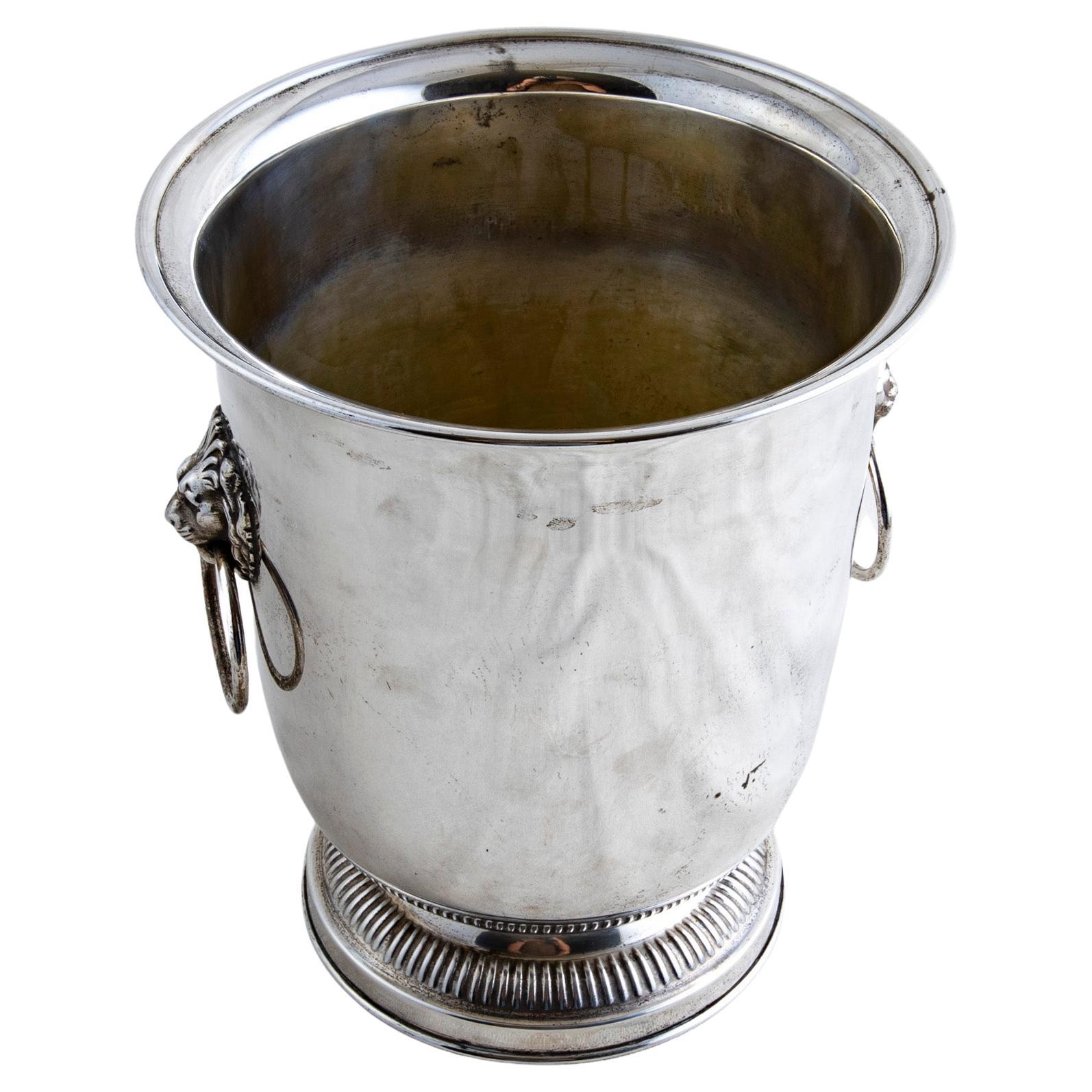 This mid-twentieth century French silver plate champagne bucket features a lion's head on each side with a drop ring handle. The bucket stands on a fluted footed base. A beautiful addition to any bar, circa 1950.