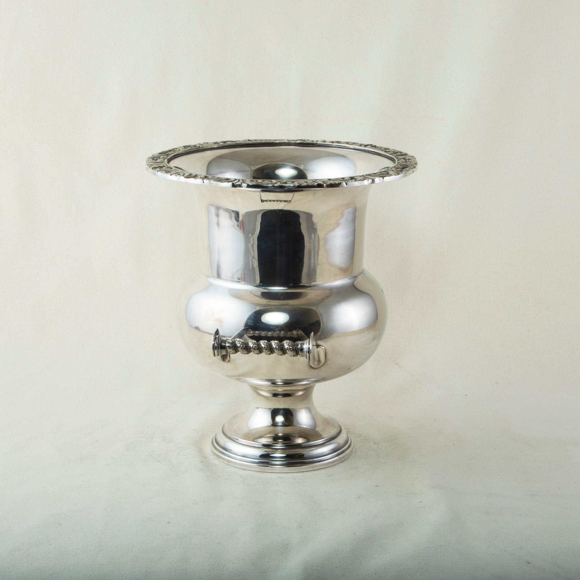 This mid-twentieth century French silver plate champagne bucket features a scrolling leaf motif around the upper rim. Its curved bowl rests on a footed base and is appointed with twisted handles detailed with grape leaves. c. 1960.