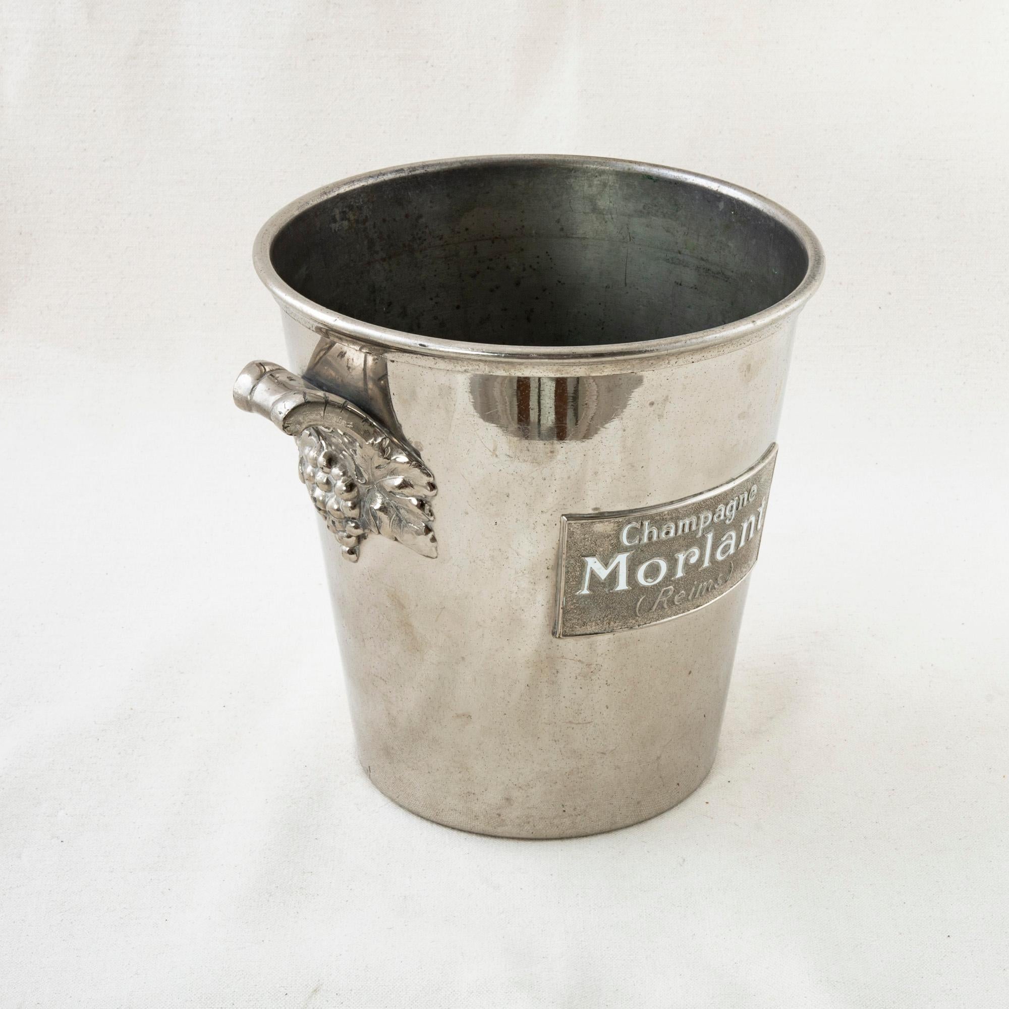This French silver plate champagne bucket from the mid-twentieth century bears the enameled label name of the champagne producer Morlant and is marked Reims. A handle on each side is adorned with grapes and grape leaves. Stamped Tete Leroy, Made in