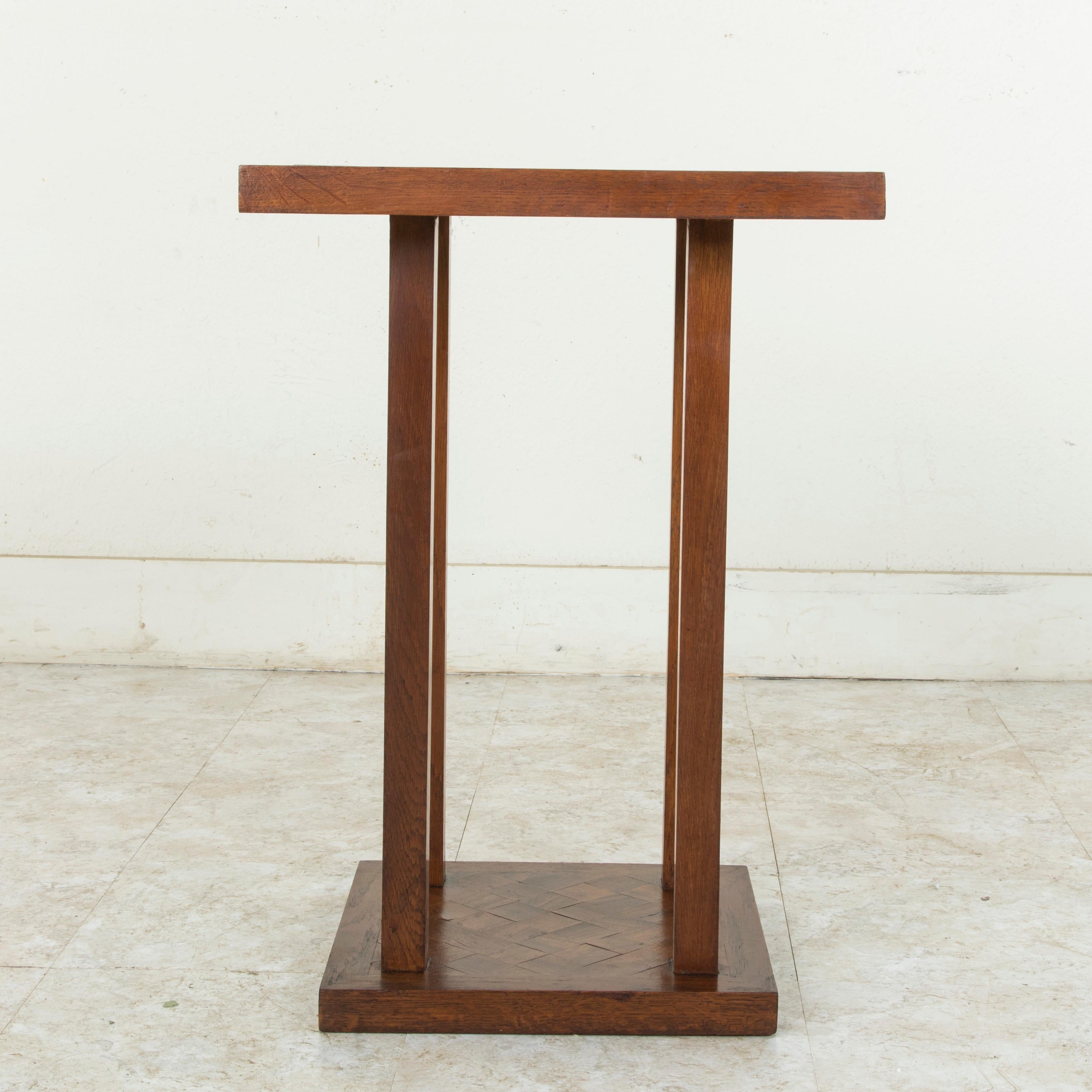 This mid-20th century French oak side table features a diamond pattern marquetry top made from one inch thick blocks. The square top is supported by four square legs that join to a lower platform. The lower platform repeats the diamond marquetry