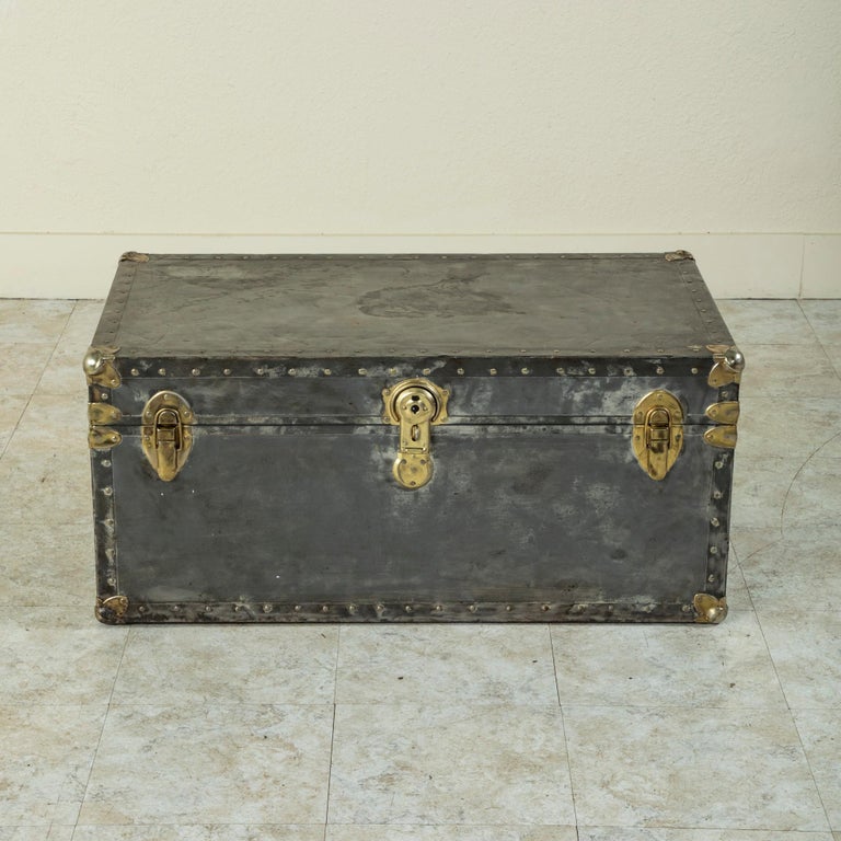 This mid-twentieth century French steel trunk features chrome corners and brass plated latches. Its original leather handles are still intact. The interior of the trunk is lined with pine. An ideal piece for use as a coffee table, circa 1940.