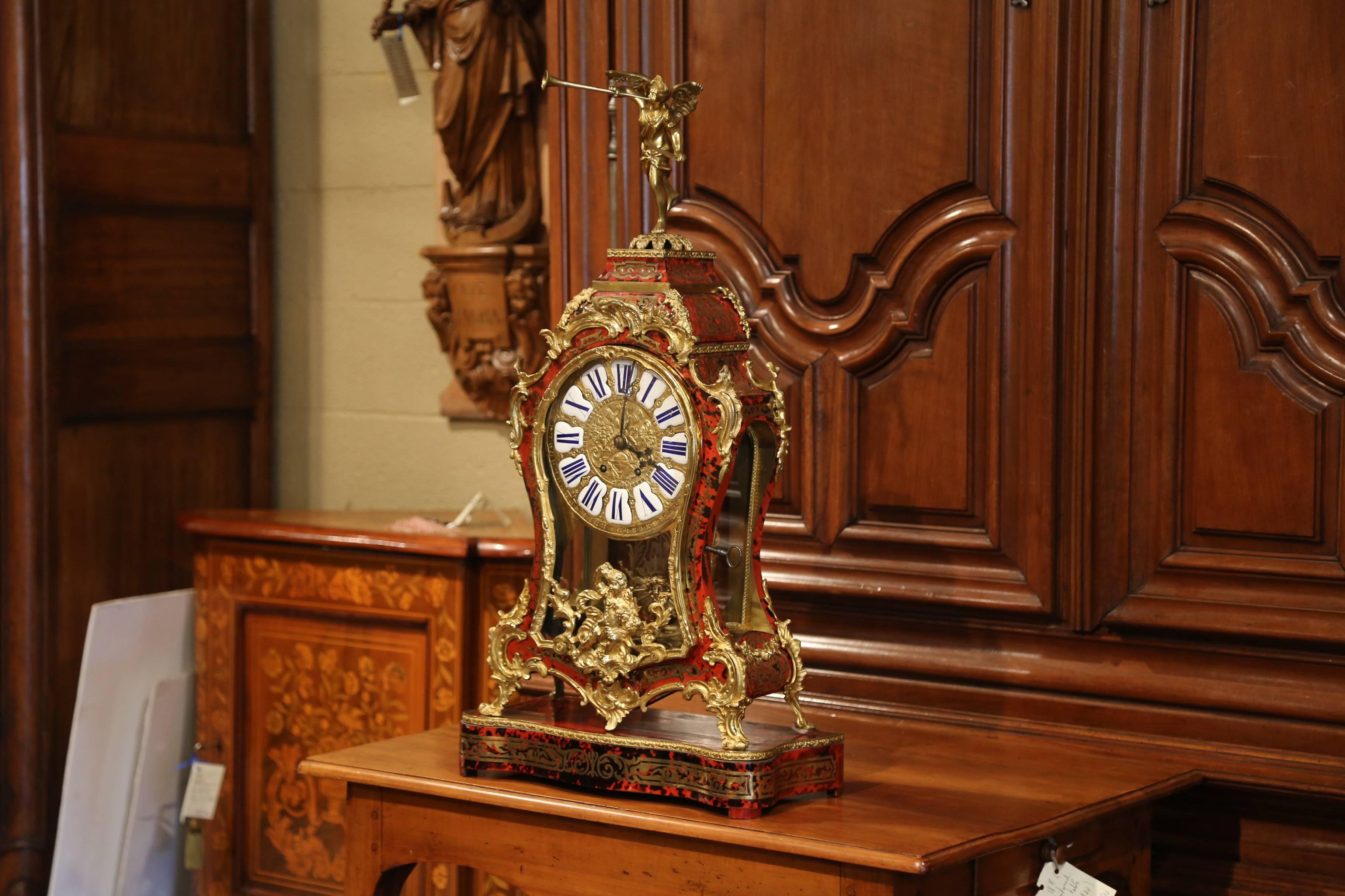 Diese bedeutende, alte Boulle-Kaminuhr wurde um 1950 in Frankreich hergestellt. Die Uhr steht auf einem Originalsockel mit verschnörkelten Bronzefüßen und dekorativen Beschlägen; sie hat einen gewölbten Giebel, der von einem Trompete spielenden