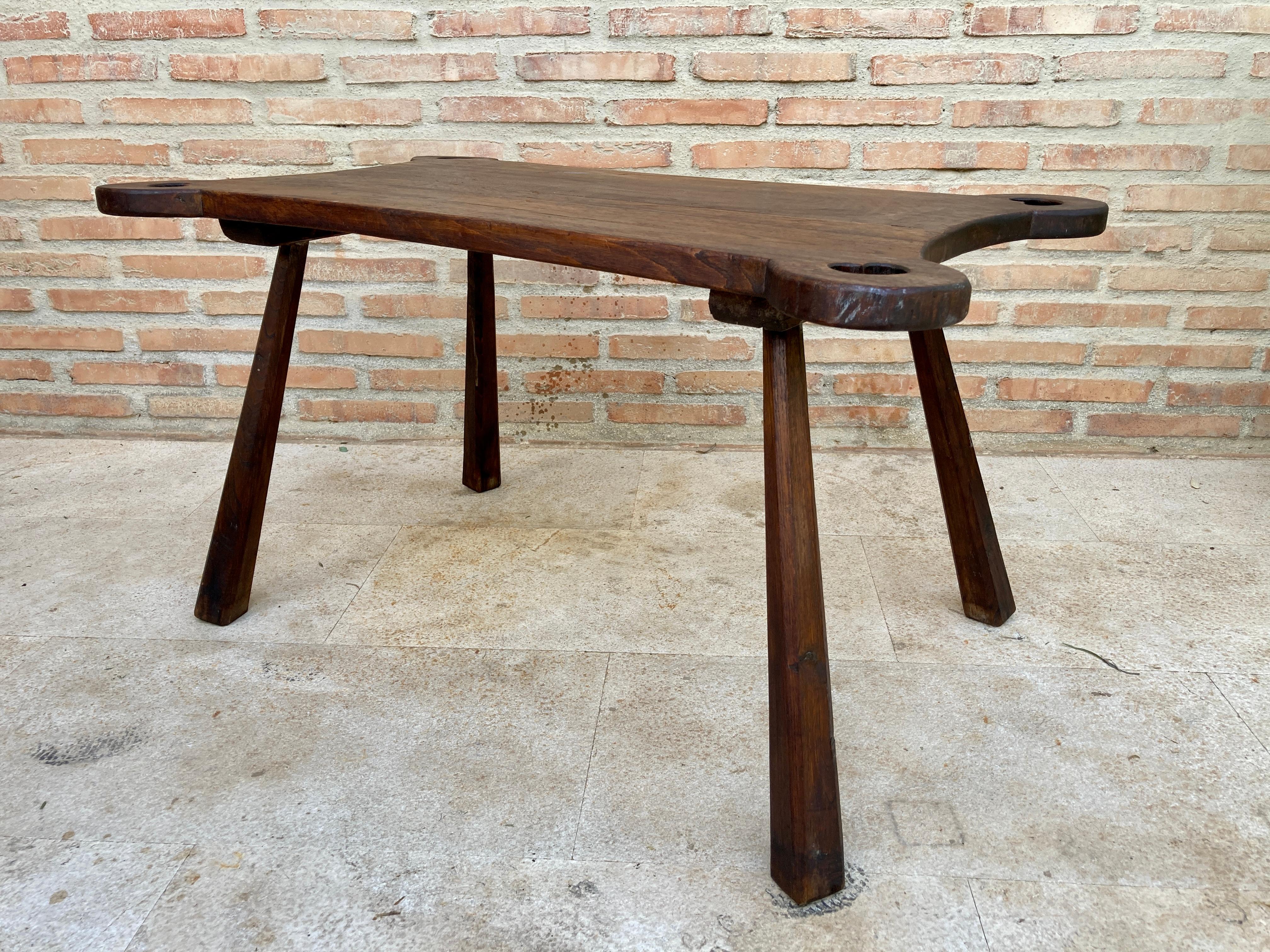 French mid-20th century side table. This rustic French side table features a thick, rectangular-shaped top with decorative holes in the four corners of the tabletop, which stands on four twig legs. The table is made of walnut wood, which has a nice