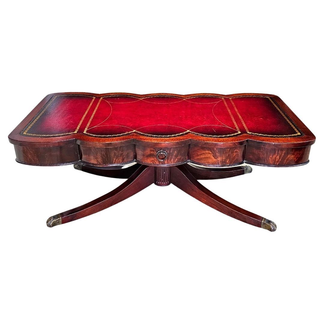 Table de style géorgien du milieu du 20e siècle en acajou crocheté avec plateau en cuir estampé 
 avec pieds en pattes de laiton Table basse à piédestal. Comprend un grand tiroir unique.
Mesure 46