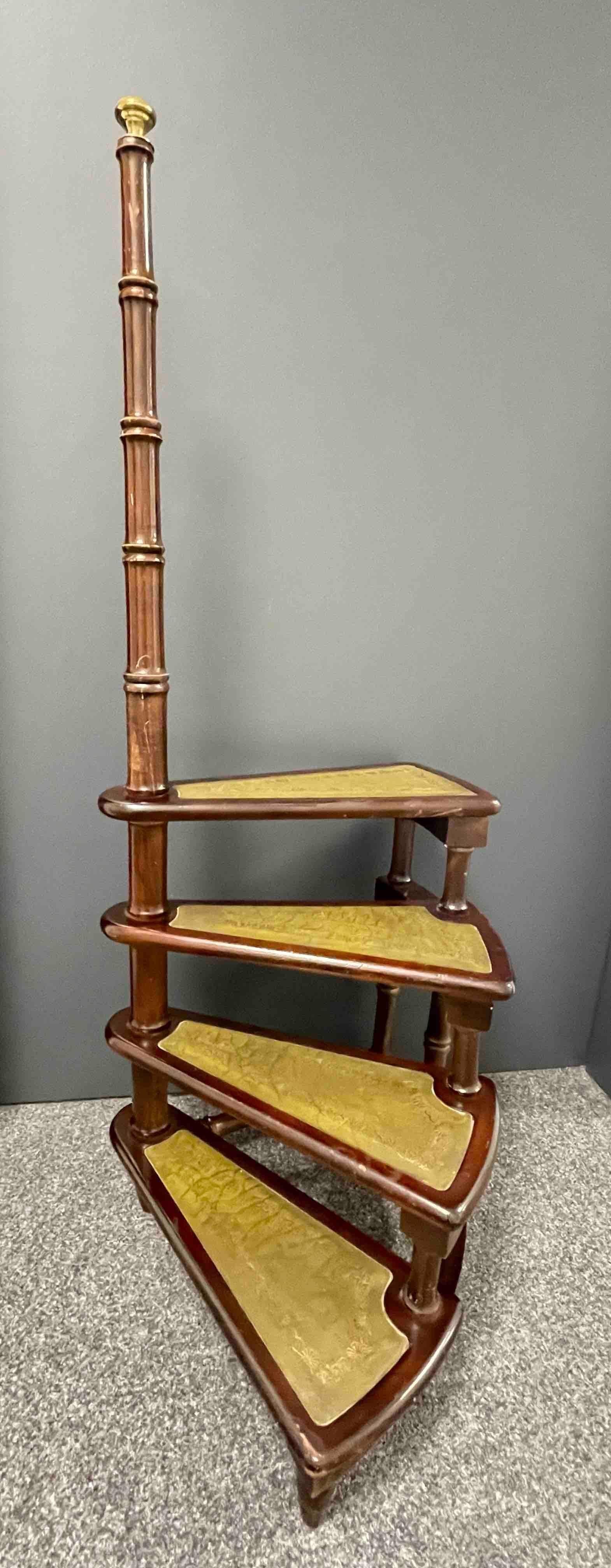 Created in Germany circa 1960 and standing on turned legs, the tall circular step ladder features four stairs rolled around a turned, central post embellished with a decorative brass finial at the pediment. Each step is upholstered with the original