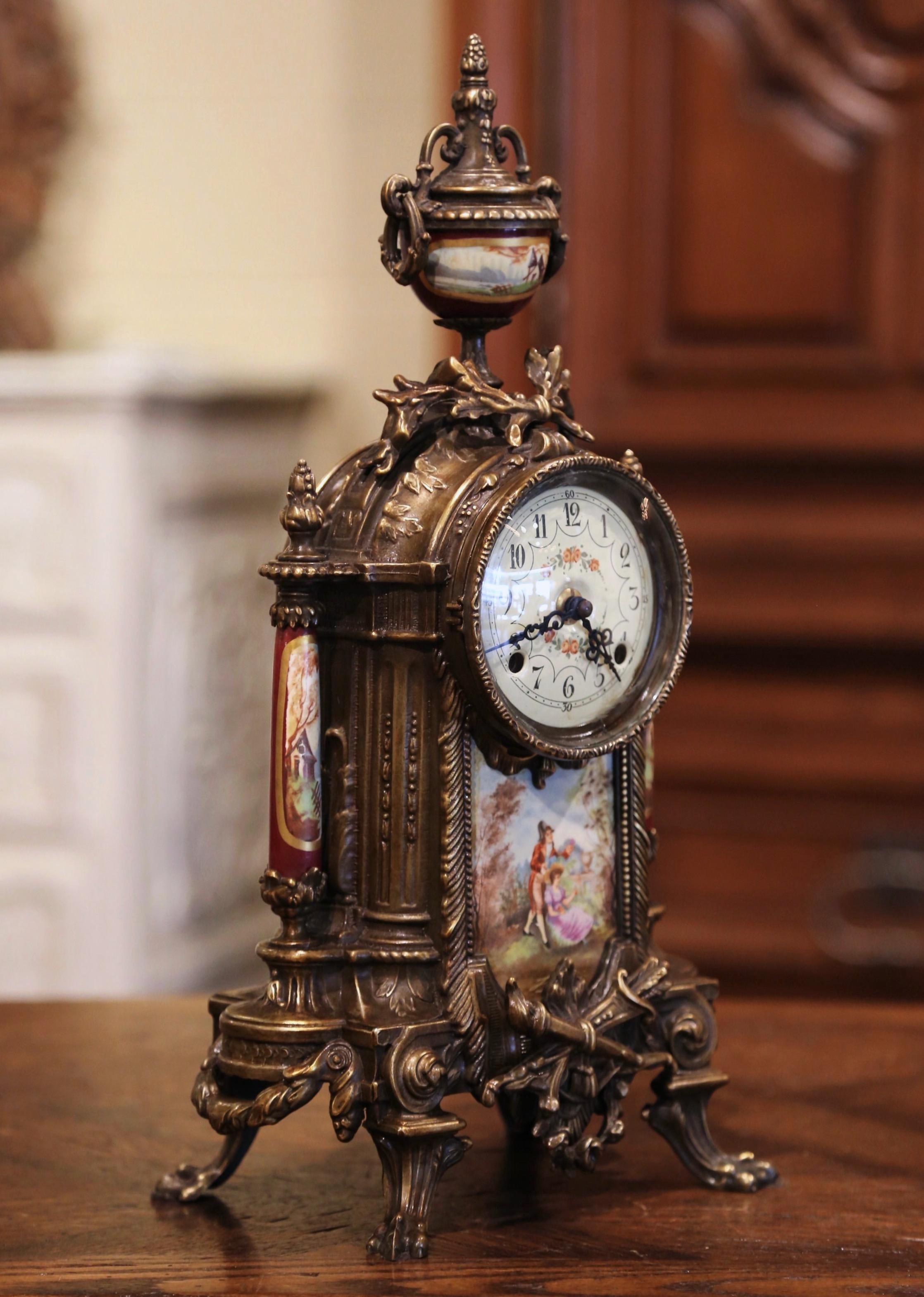 Place this antique clock on a mantel or a desk; crafted in Germany circa 1950, the elegant time keeper sits on four paw feet over an intricate apron decorated with torch and swag motifs. The bronze clock is decorated with painted porcelain column on
