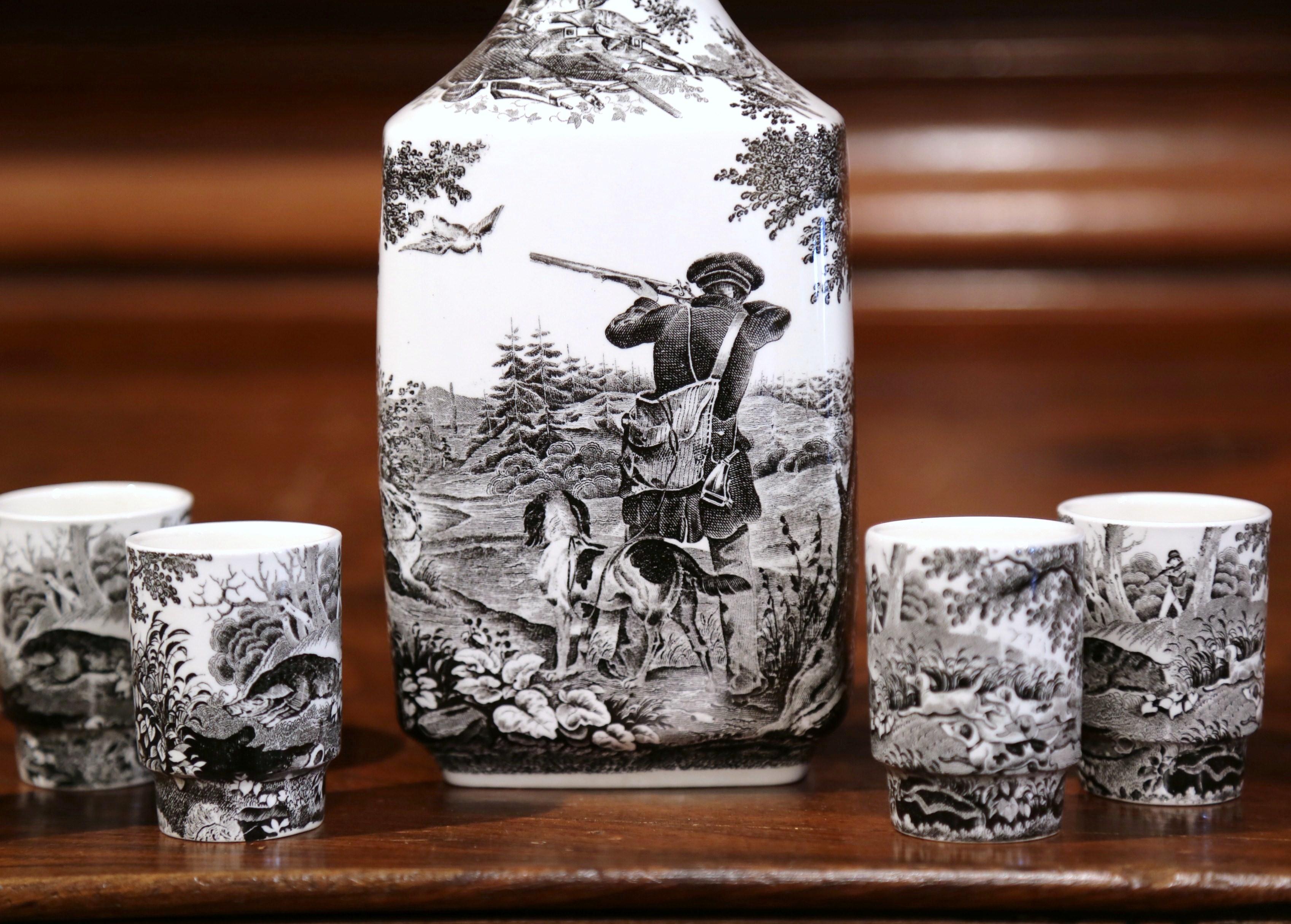 This elegant, porcelain liquor set was crafted in Germany in 1950, and features a hunting scene in a traditional, European style. The hand painted black and white porcelain set comprises a decanter with a stopper and four complementary shot glasses.