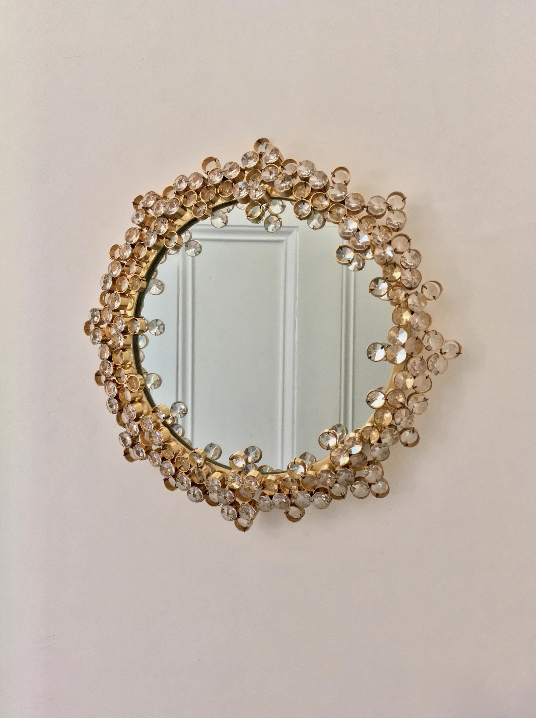 A charming wall-mounted circular vanity mirror in a gilt-brass frame, with decorative surround of high quality crystal pieces. Attributed to Palme and Walter (or Palwa), second half of the 20th century.

Well-designed and constructed piece, with a