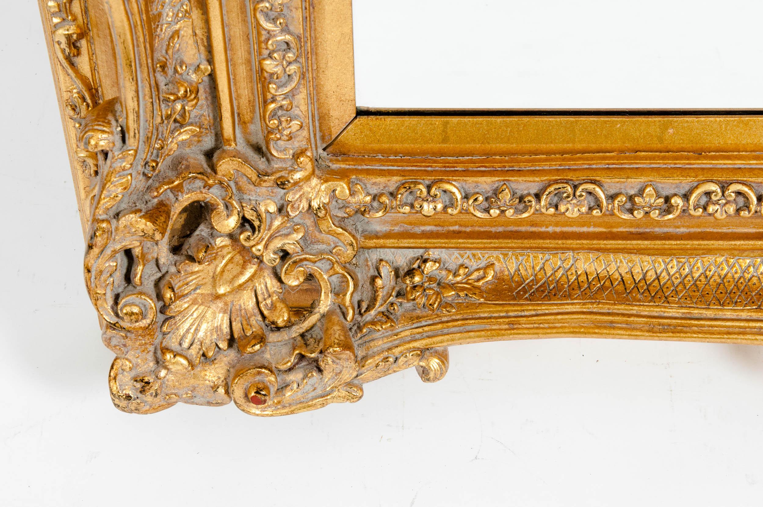 Mid-20th century ornately giltwood frame bevelled mantel hanging wall mirror. The mirror is in excellent condition with appropriate wear consistent with age and use. The wall mirror measure about 49 inches length x 37 inches wide x 5 inches deep.