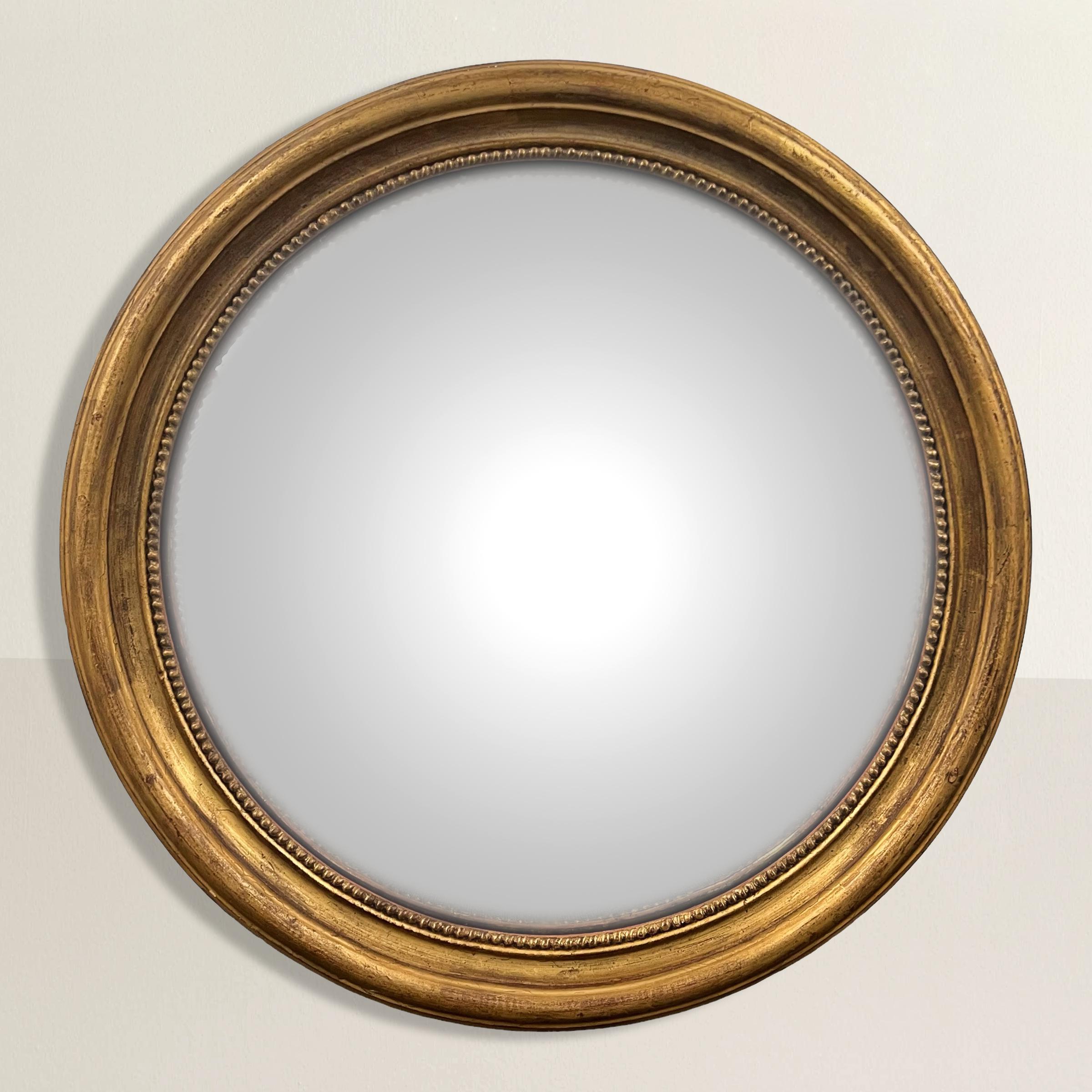 Lassen Sie sich von der Opulenz des neoklassischen Designs inspirieren, mit diesem atemberaubenden großen runden, konvexen Spiegel mit vergoldetem Holzrahmen aus dem 20. Sein filigraner Rahmen erinnert an die Erhabenheit des klassischen Designs und
