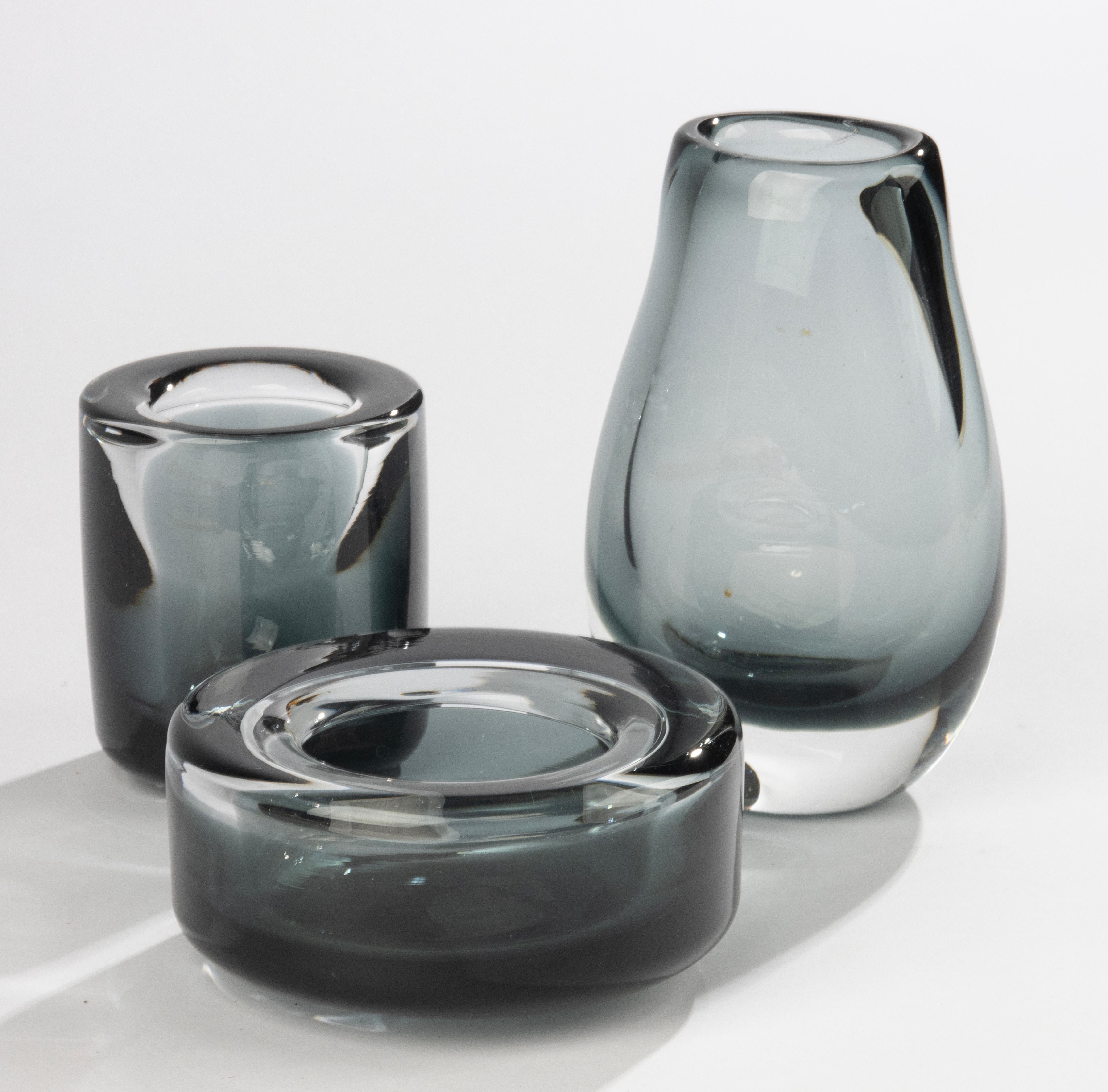 Elegantes Set aus drei Glasobjekten, entworfen und hergestellt von der schwedischen Firma SEA Glasbruk. Die Stücke sind aus dickwandigem Glas mit schön abgerundeten Kanten und einer raffinierten rauchgrauen Farbpalette gefertigt, die typisch für das