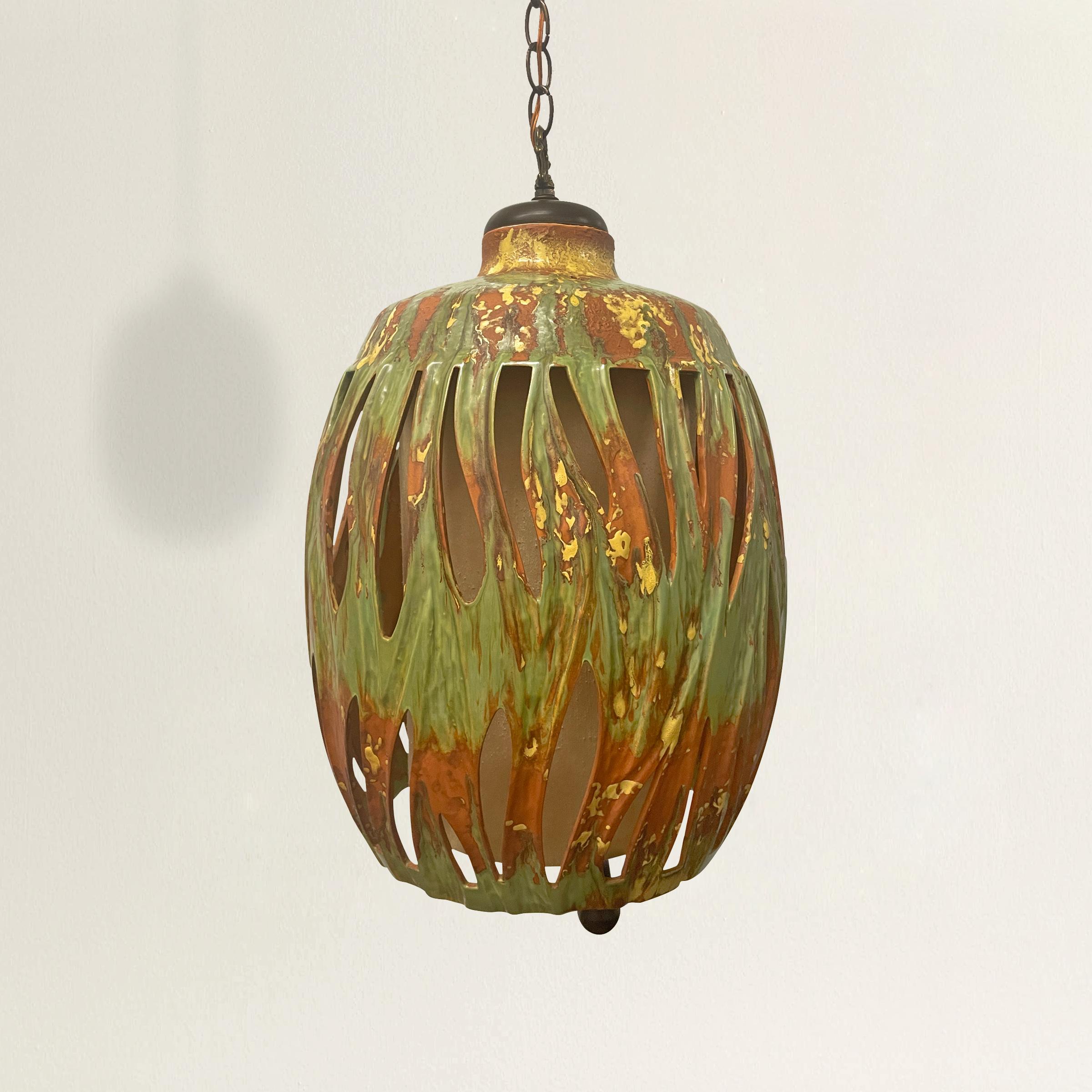 A groovy mid-20th century American terracotta lantern with the best green and yellow splatter glaze, a cylindrical raw silk shade, and a chunky wood pull chain. Electrified for US. Approximately 6 feet of lead wire and chain included.