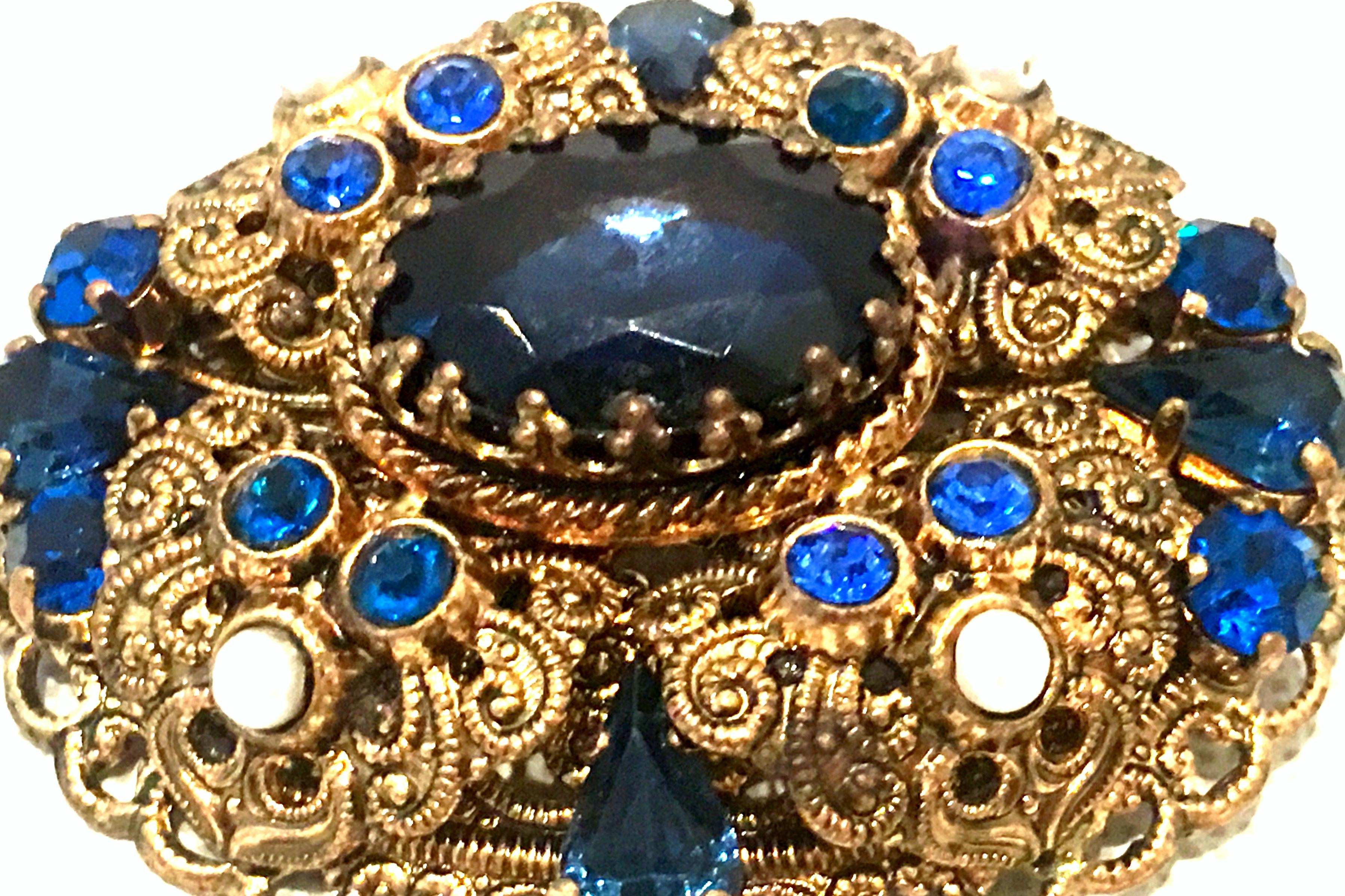 Mid-20th Century Gold Vermeil & Austrian Crystal Brooch-Signed, West Germany.
This oval gold vermeil  dimensional brooch features delicate and intricate filigree work with brilliant cut and faceted Austrian crystal sapphire blue stones and white
