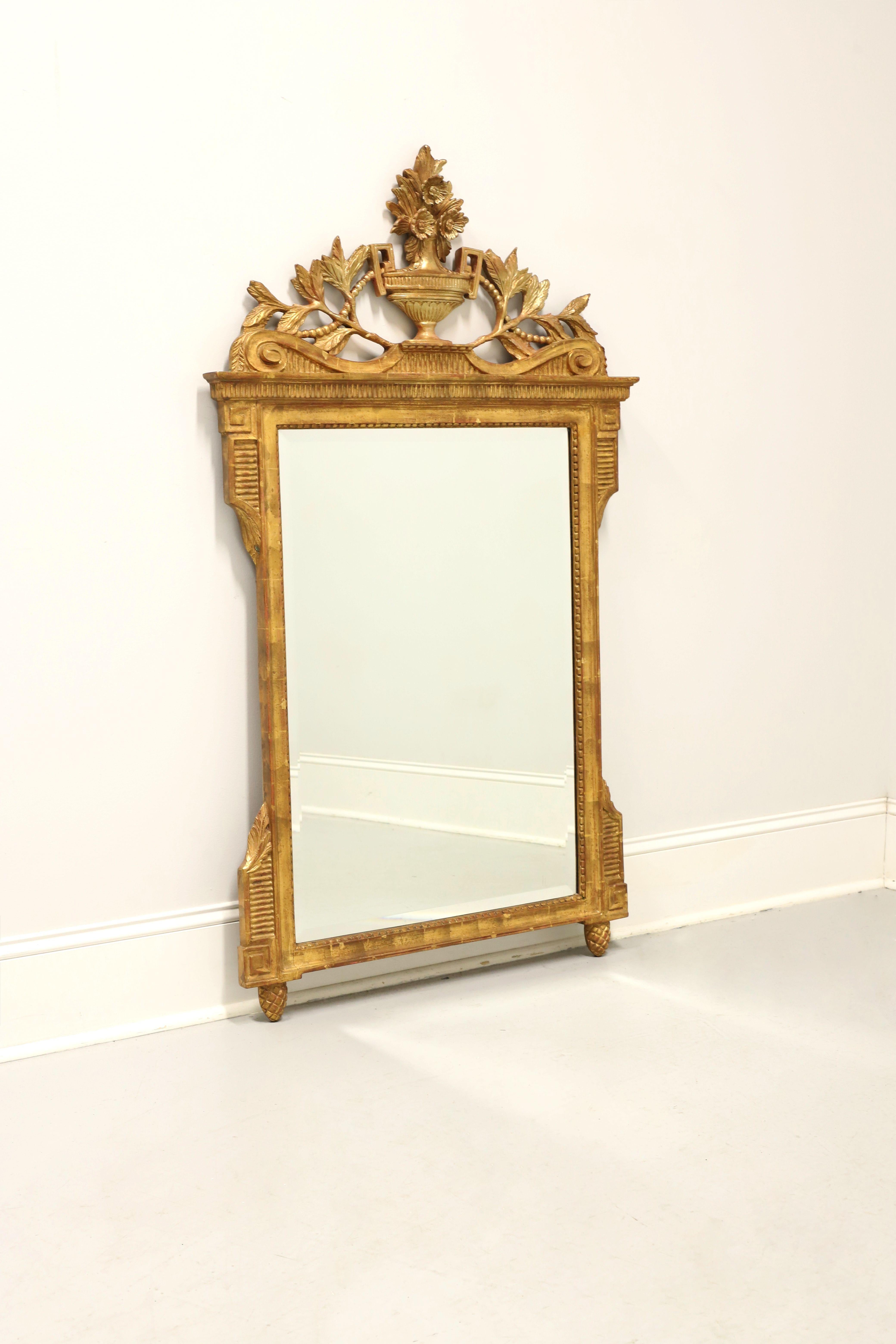 A Neoclassical style wall mirror, unbranded. Beveled mirror glass in an ornate gold gilt composite frame with architectural design elements, wood foliate ornamentation to top, center urn with floral motif to top center, and pineapple reverse finials