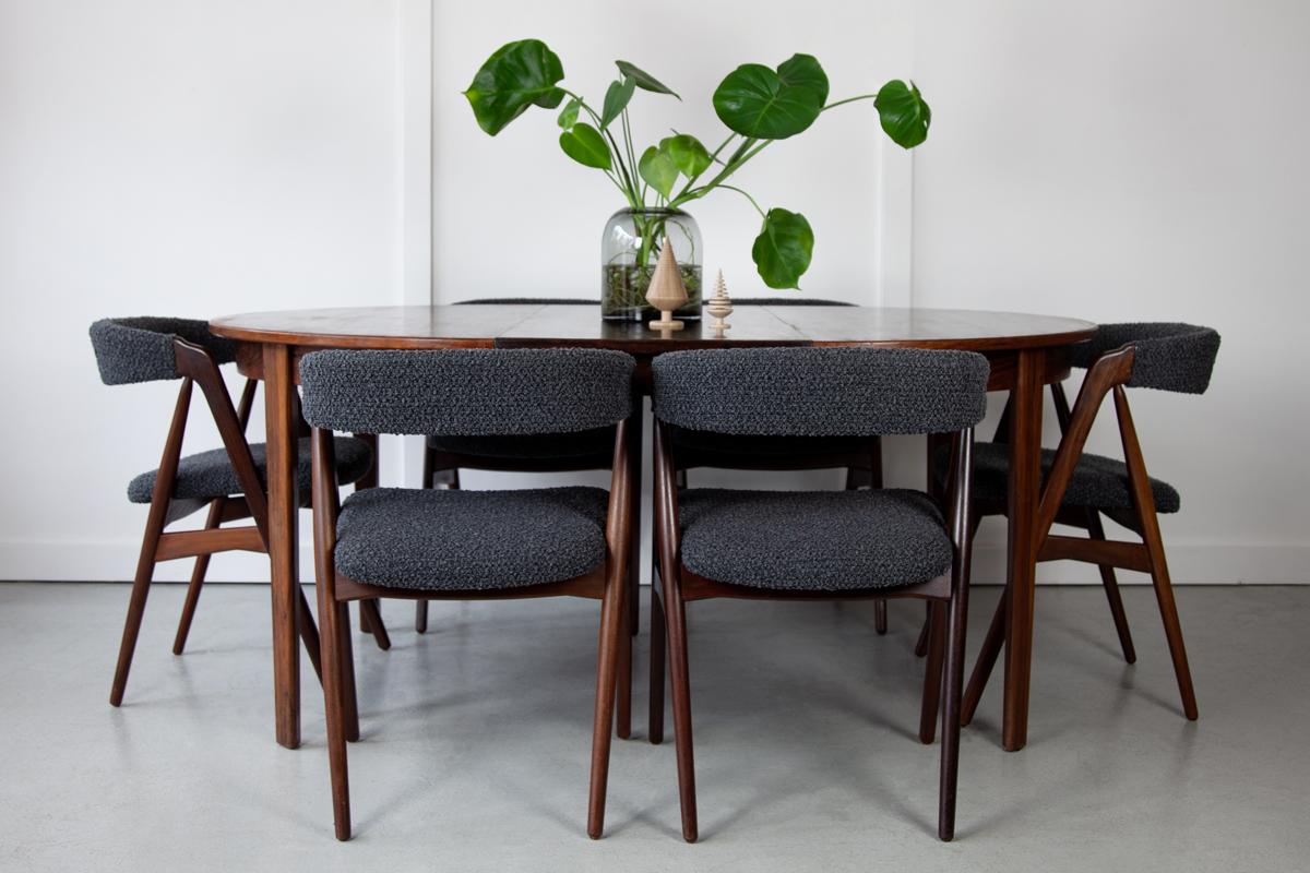 An extendable dining table in rosewood, designed by Gunni Omann for Omann Jun Møbelfabrik. Two separate leaves slot into the middle section, one by one, to extend the table to a large oval size. Standing on elegantly tapering legs, this dining table